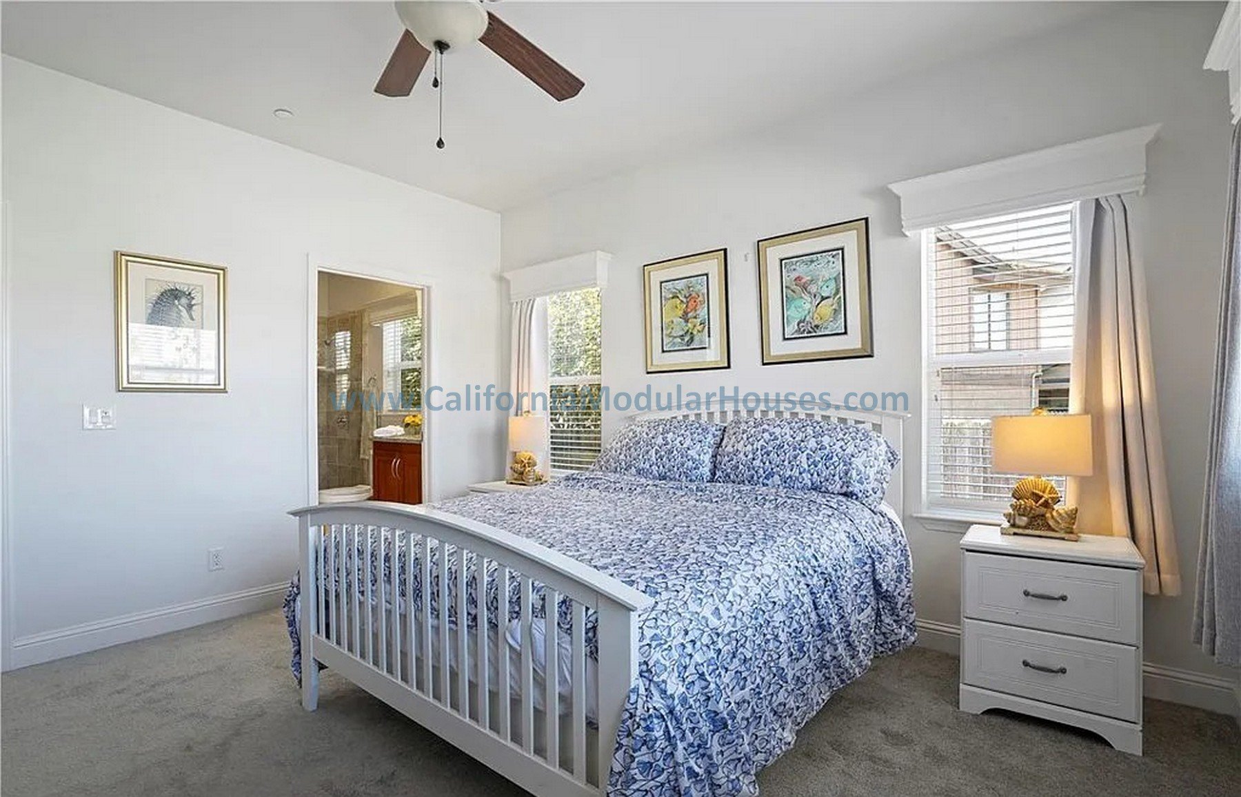 Bedroom with white walls.  There is a ceiling fan and windows with white curtains.  California Modular Houses. Pre fab home.  Modular homes for California.  Casas prefabricadas.  Southern California.  