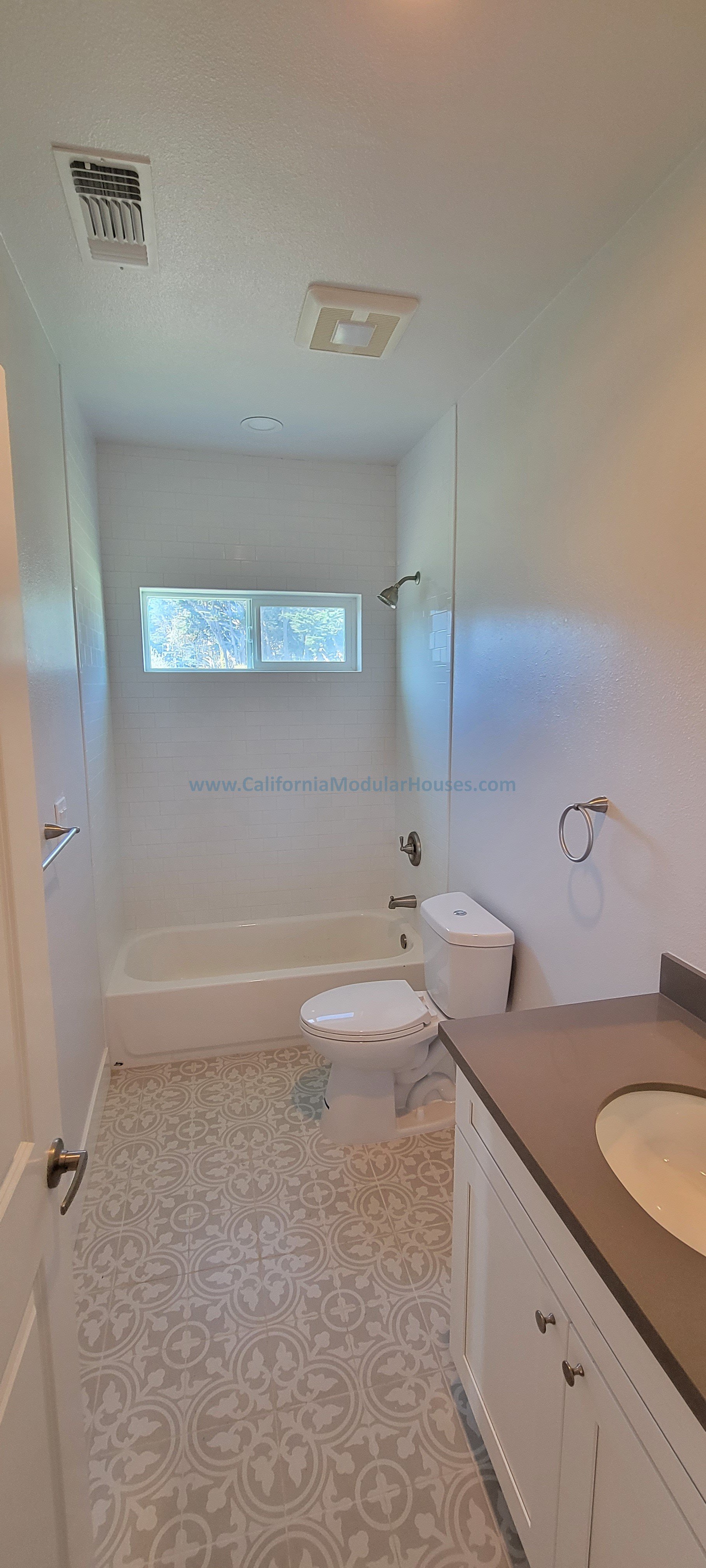Bathroom with a bathtub and shower, toilet, vanity with sink, and window.