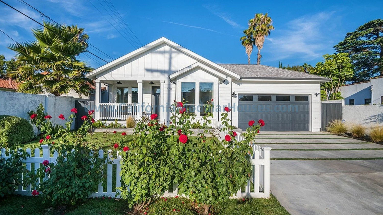 This pre-fab home shows a perspective of how beautiful the gable roof is and how much curb appeal there is with a nice driveway, small fence, and beautiful roses to add color.  