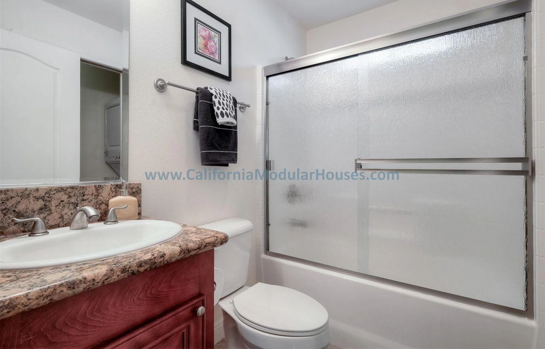 Bathroom with a granite countertop sink, a cabinet, a toilet, a frosted glass shower with a sliding door.  The Teal Prefab Accessory Dwelling Unit.  Modular Homes.  Modulars for Martinez, Contra Costa County, CA.  Pre-fabricated homes.  Prefab ADU.  