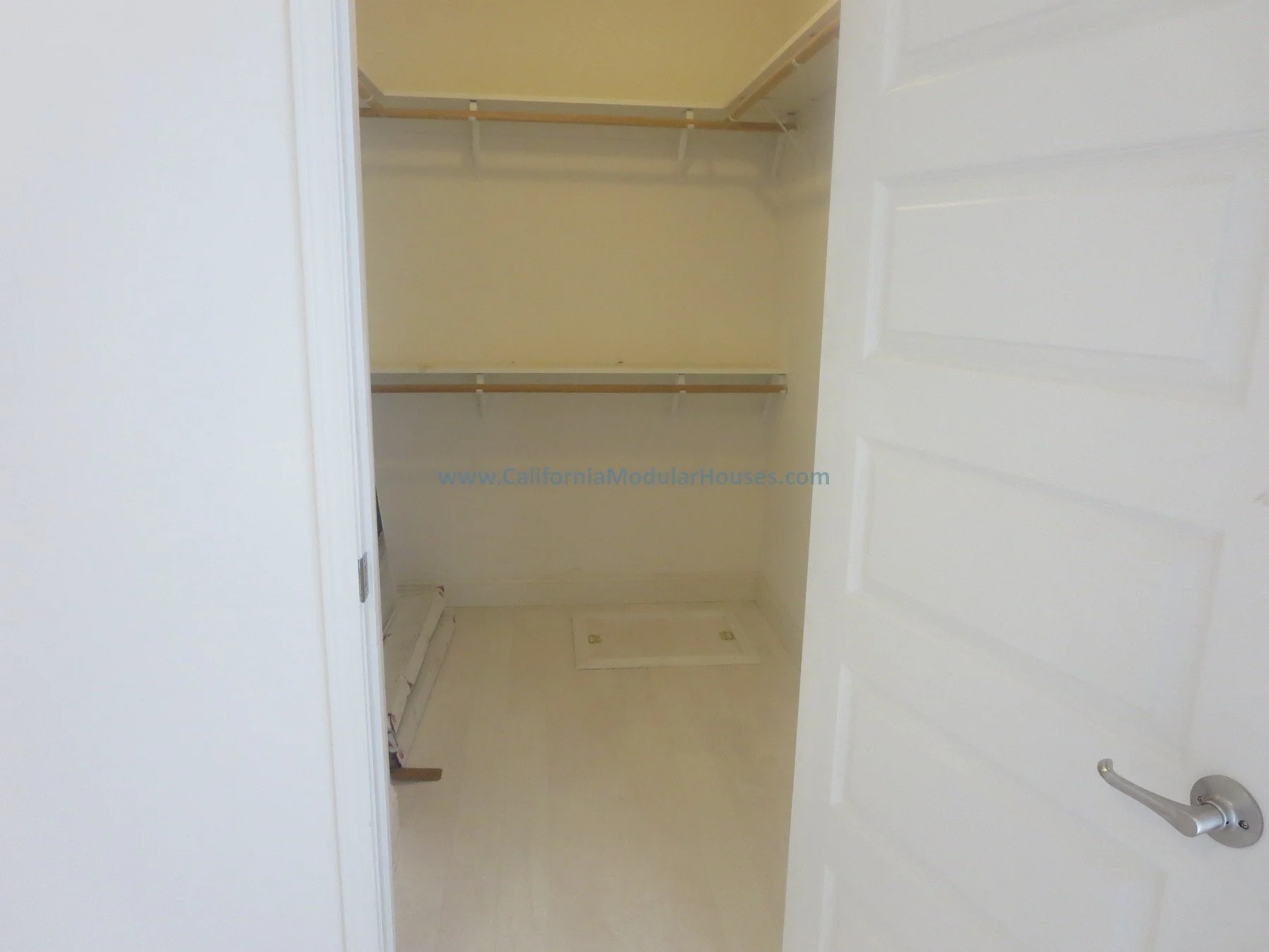 Modulars for Napa.  Napa County, CA. Modular. Pre-fab Modular.   Modulars for Napa.  Cape Cod.   Empty walk-in closet with white shelves and hanging rods, door partially open.