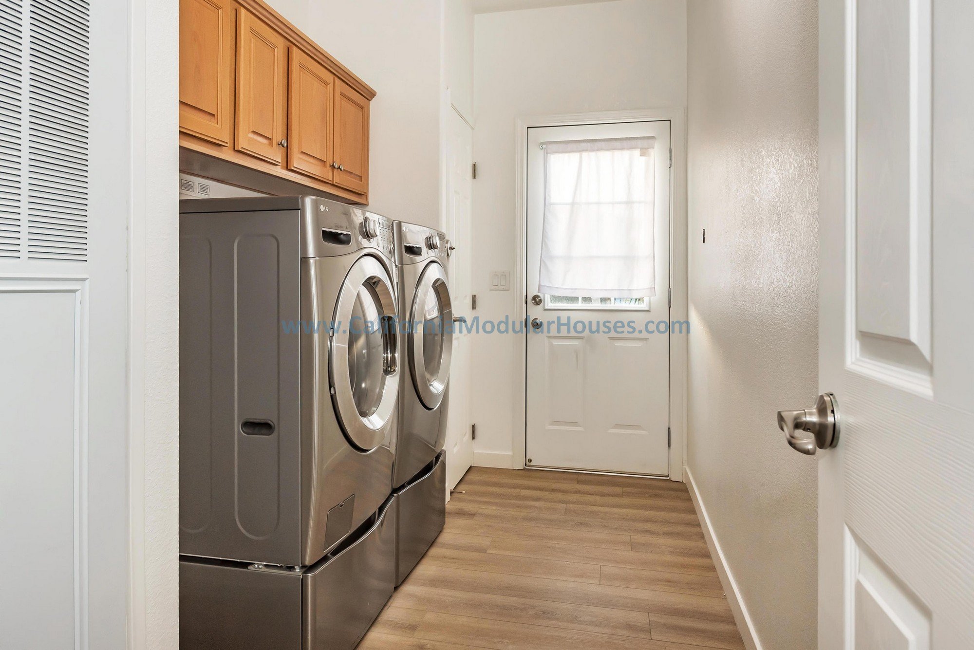 Cherry oak cabinets, white quartz countertop, stainless steel appliances of a laundry room/mud room of a prefab modular two-story home.