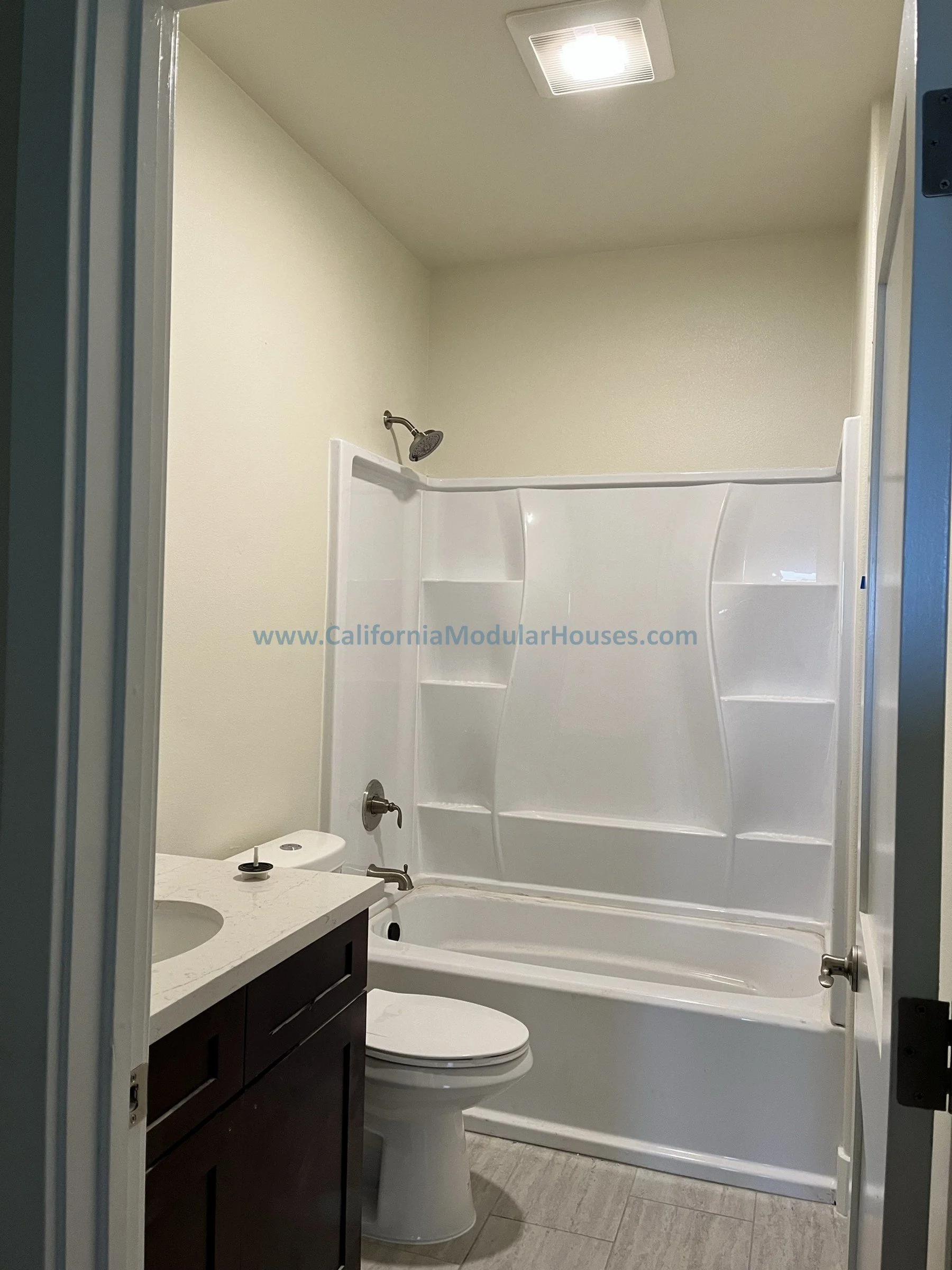 Bathroom with a bathtub and shower, a toilet, a dark wood vanity with a sink, and a ceiling light.