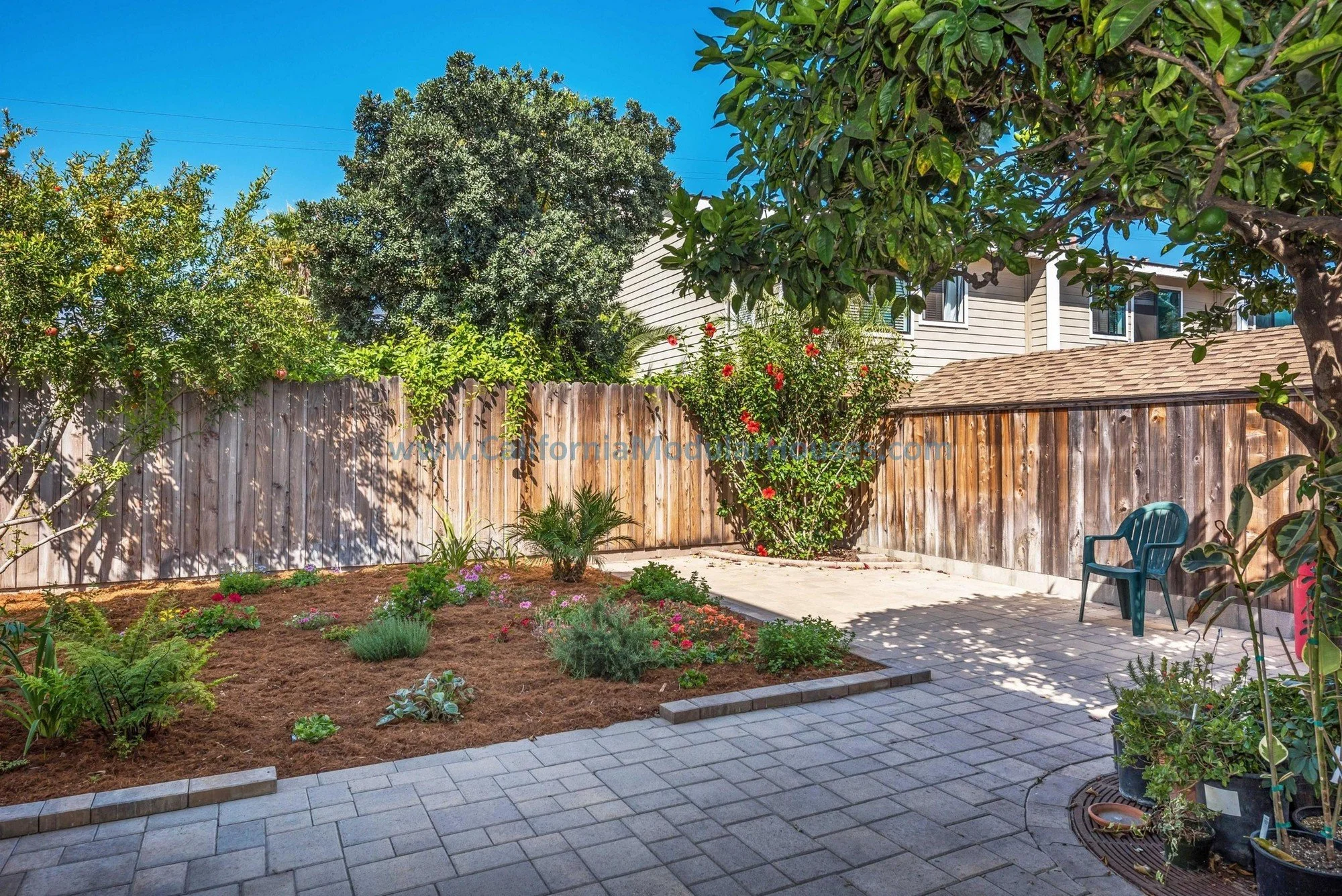 Backyard view of a sage green, brown trim prefab modular, two-story home.