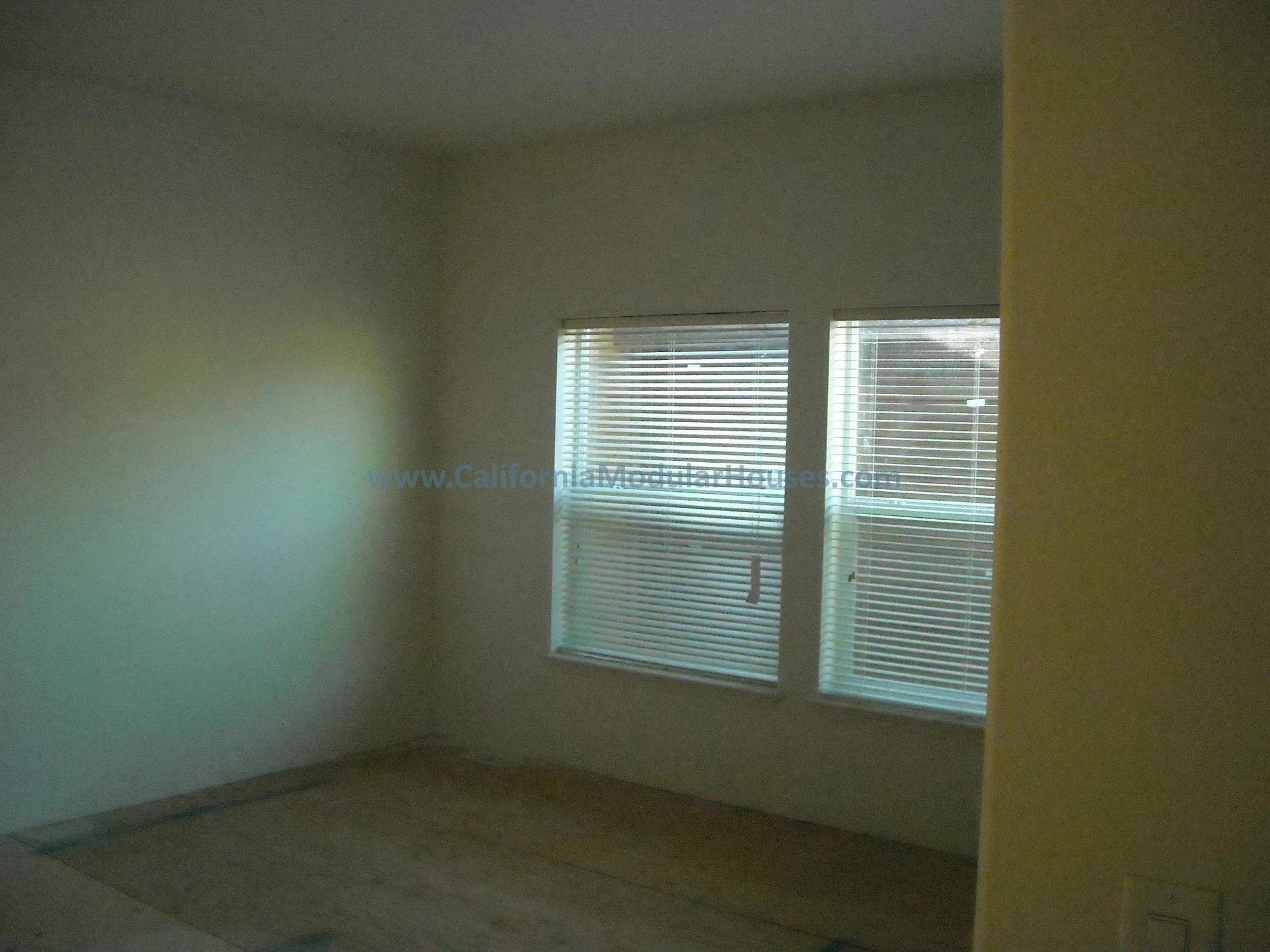 Bedroom with two windows covered by blinds in this factory built home, redesigned specifically to meet the client's needs and also meet their interior and exterior aesthetic needs / requirements.  