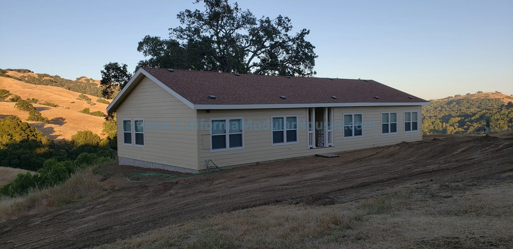 Large ranch style prefab modular home, yellow cream color, white trim, red red roof in San Jose, California