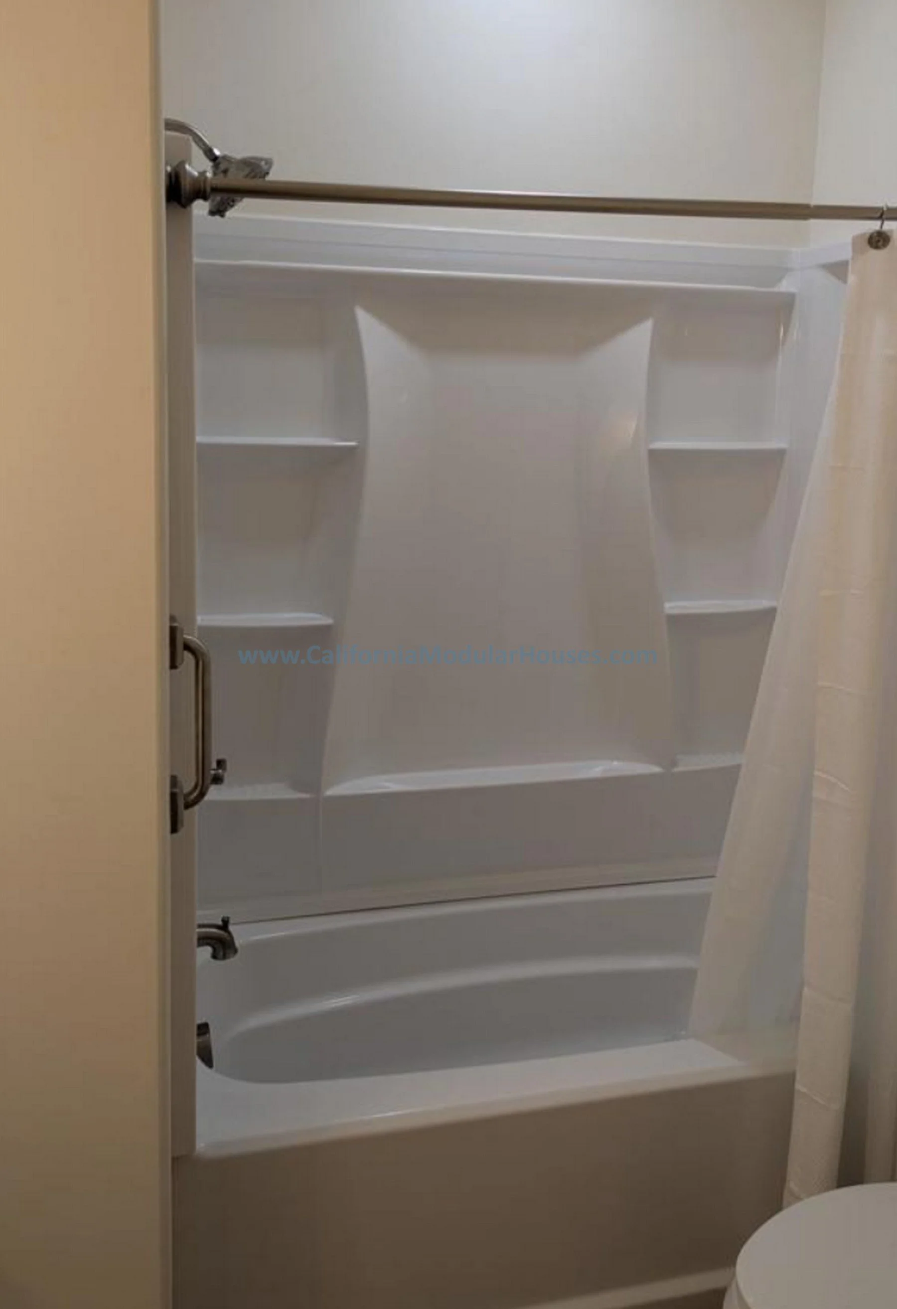 Bathroom with a corner shower with glass door, white shelves, and beige walls.  Prefab Modular ADU, Oceanside CA.  Accessory Dwelling Unit.  California Modulars.  San Diego County, CA.