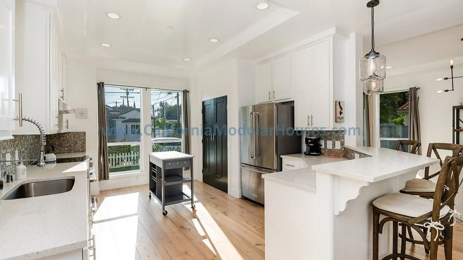 Modern white kitchen with stainless steel appliances provided by the client and a pantry.    This shows the coffered ceiling with recessed canned lights and the bay window brings in lots of natural light.  Pre-fab home.  