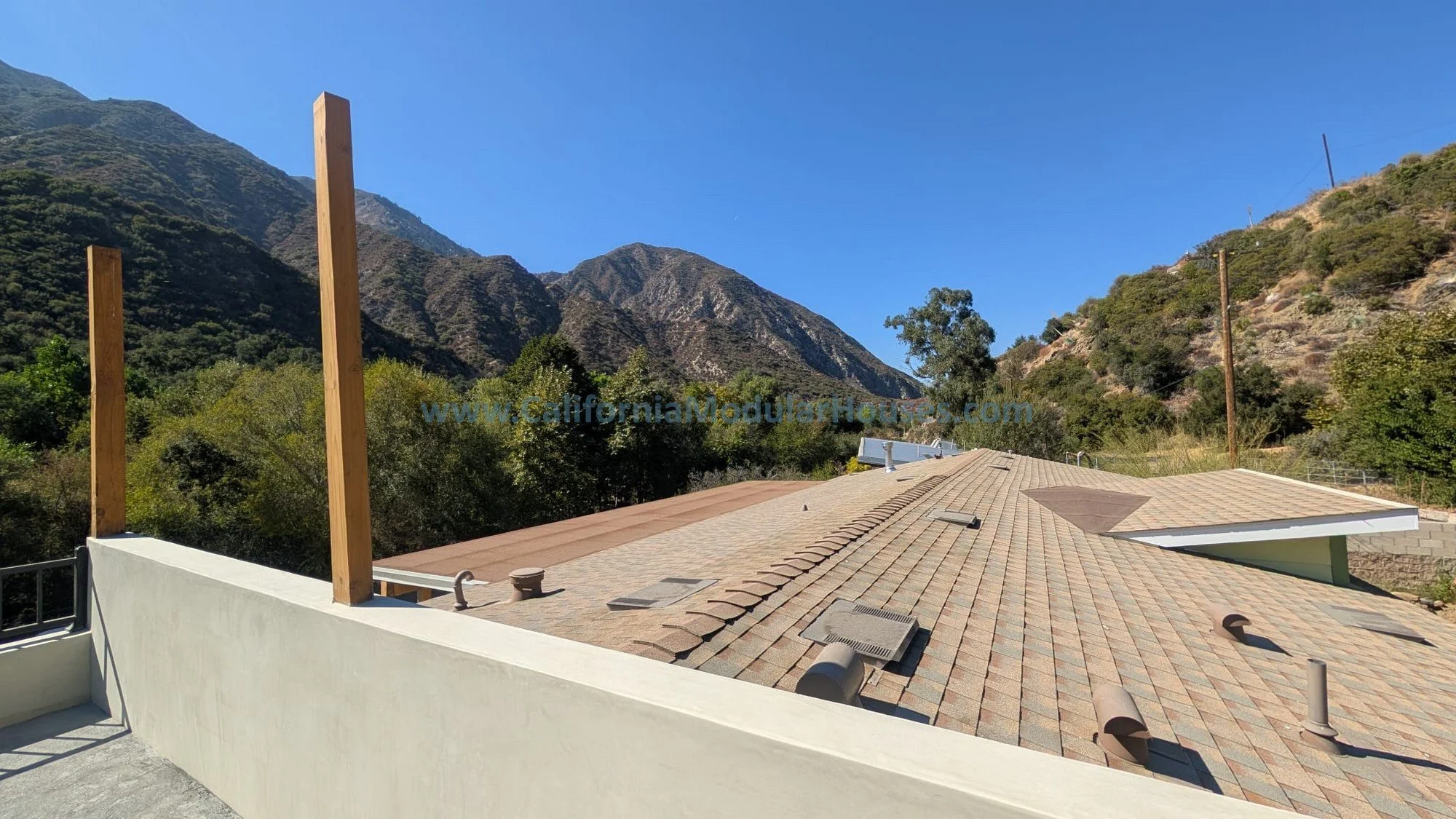 Rooftop with multiple vents and skylights, with mountains and clear blue sky in the background.