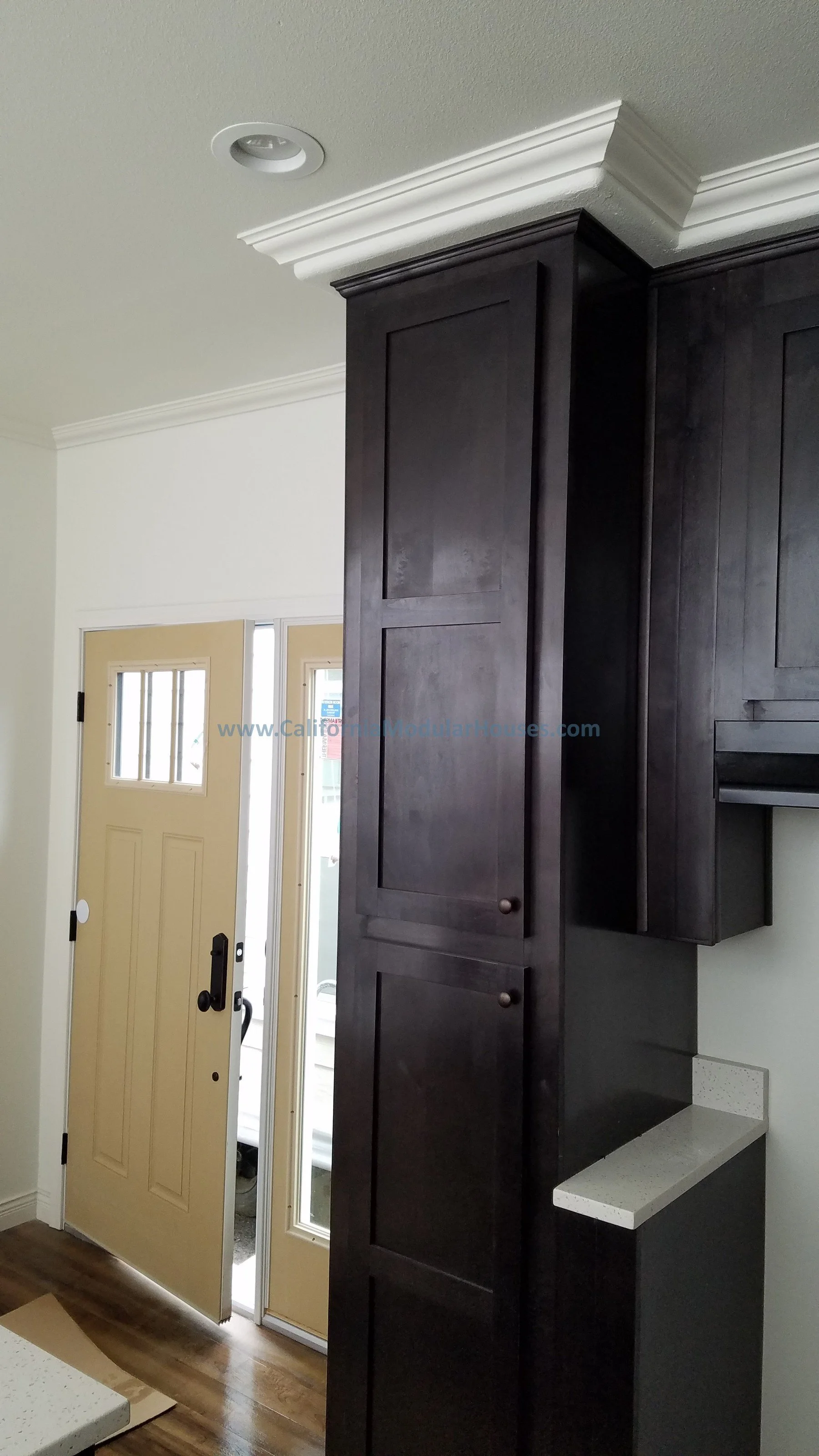 Interior view of a house entrance with a yellow door, black cabinetry, and crown molding on the ceiling.  City of Santa Barbara, Santa Barbara County, CA.  Modular Home CA, California Modular Homes,