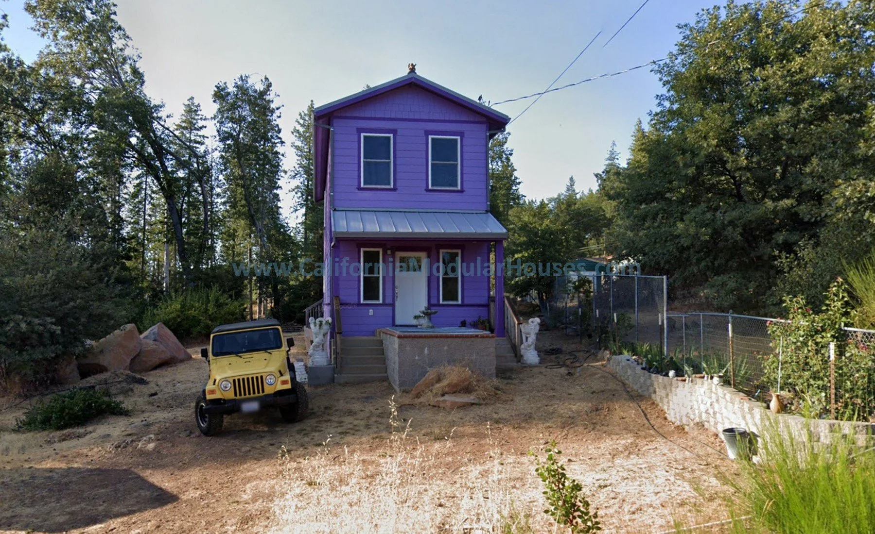 Purple two-story house with a metal roof, front porch, and decorative columns, set on a clearing with trees in the background.. Cobb Mountain, Lake County, California.  Modular Home CA, Modular Homes,