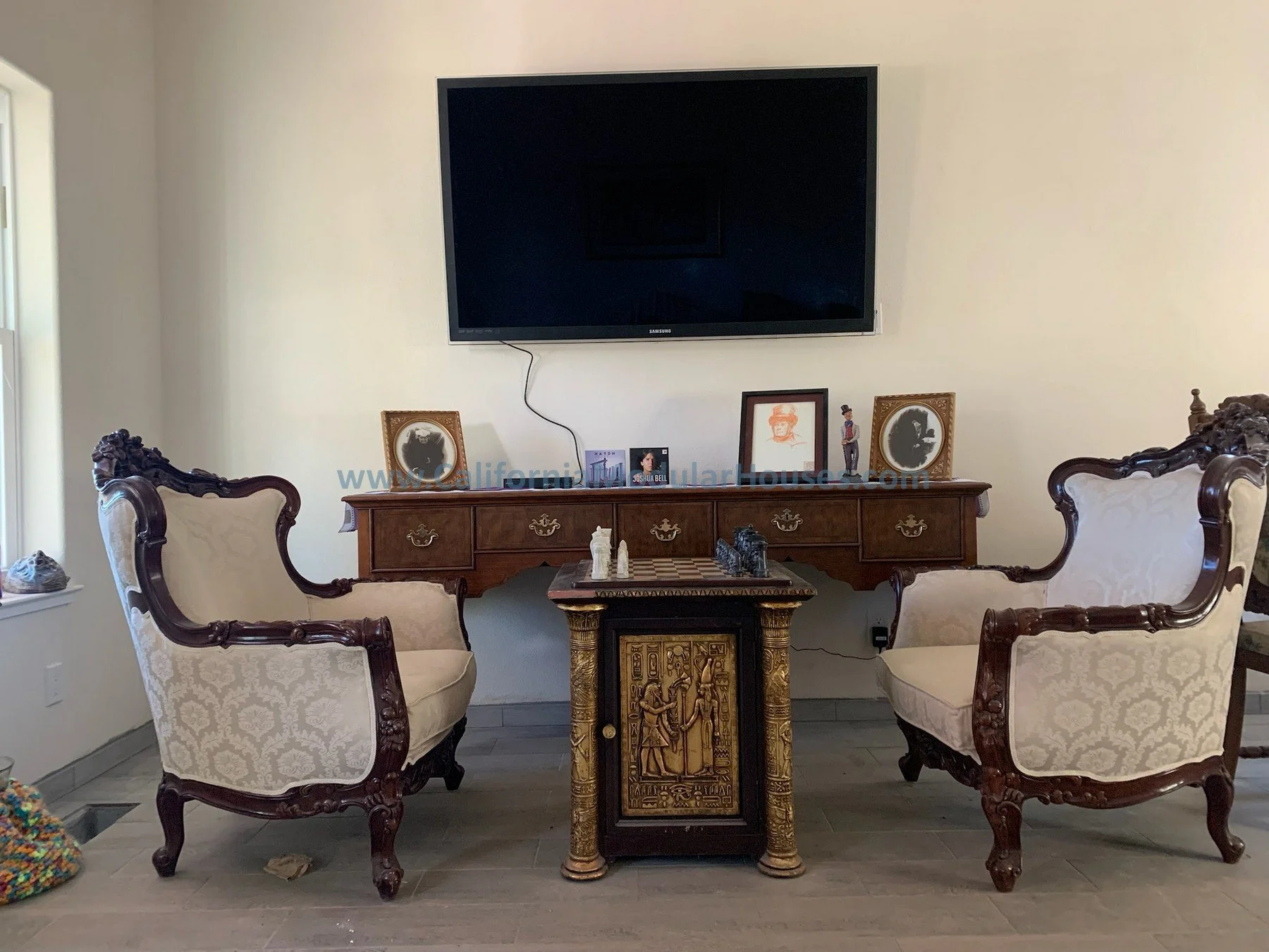 Living room with two vintage armchairs with cream upholstery and dark wooden frames and a large flat-screen TV mounted on the wall.  Cobb Mountain, Lake County, California.  The San Ysidro Falls model.  Modular Homes Northern California, CA Modular