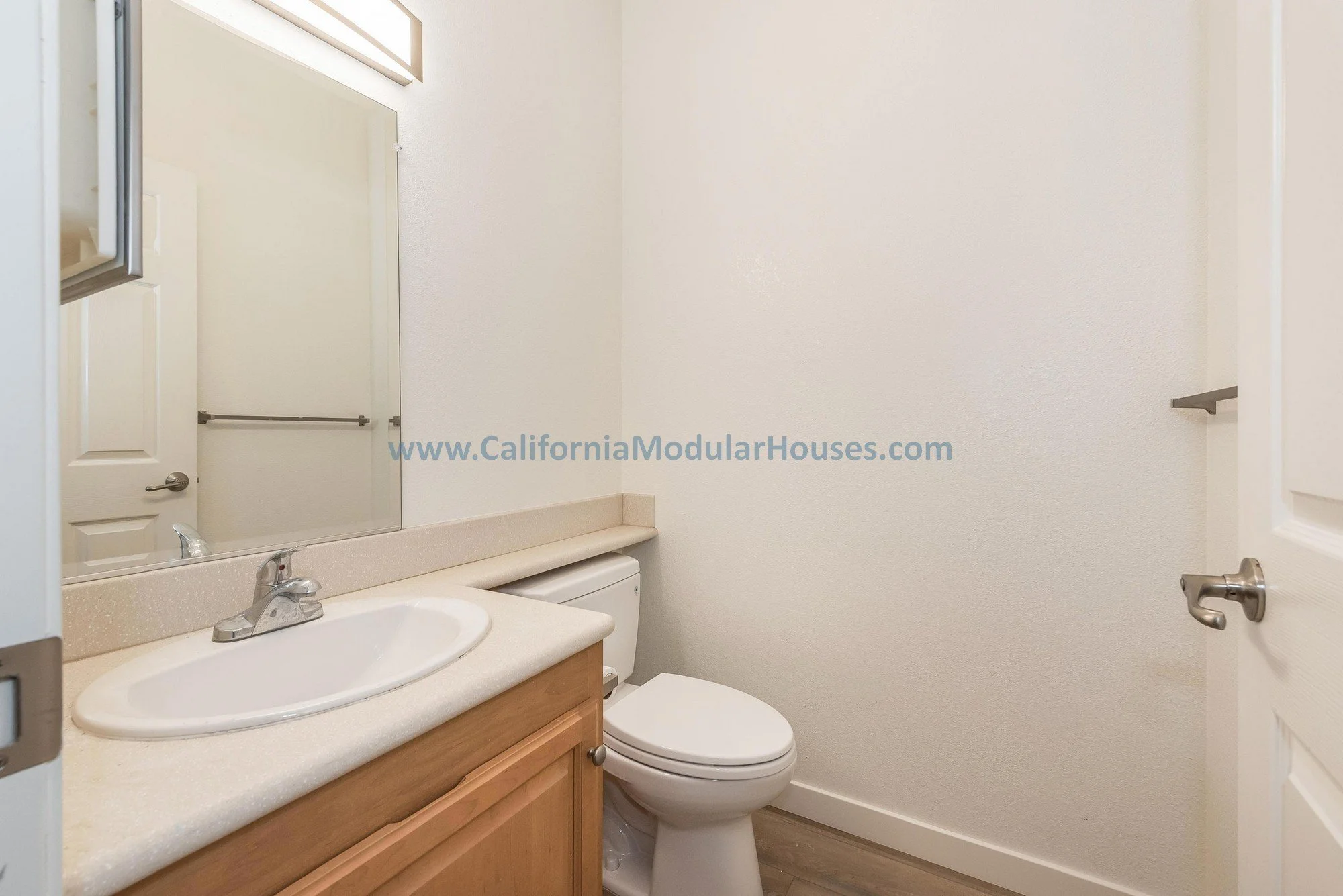 Cherry oak cabinets, white quartz countertop, porcelain sink of a guest bathroom of a prefab modular two-story home.
