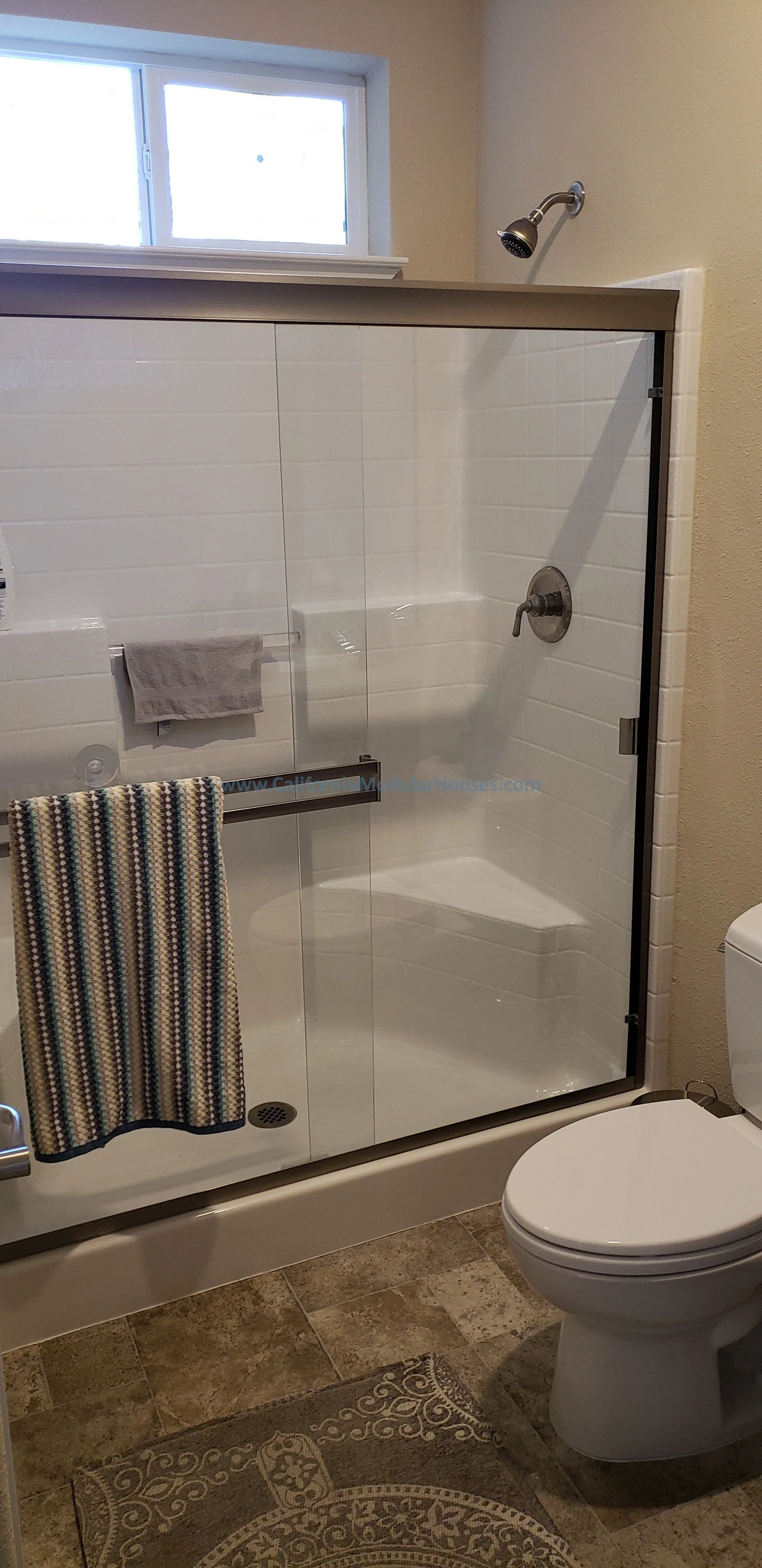In this modular home you have a composite shower with a glass enclosure, a water closet.  The window over the shower lets light in and also provides ventilation.  The floor has been tiled on-site.  