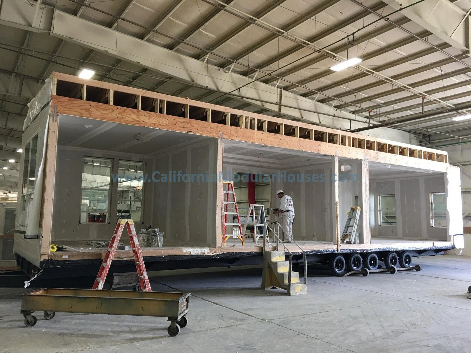 Modular house inside the factory with workers, ladders, and tools building a single family residence.  