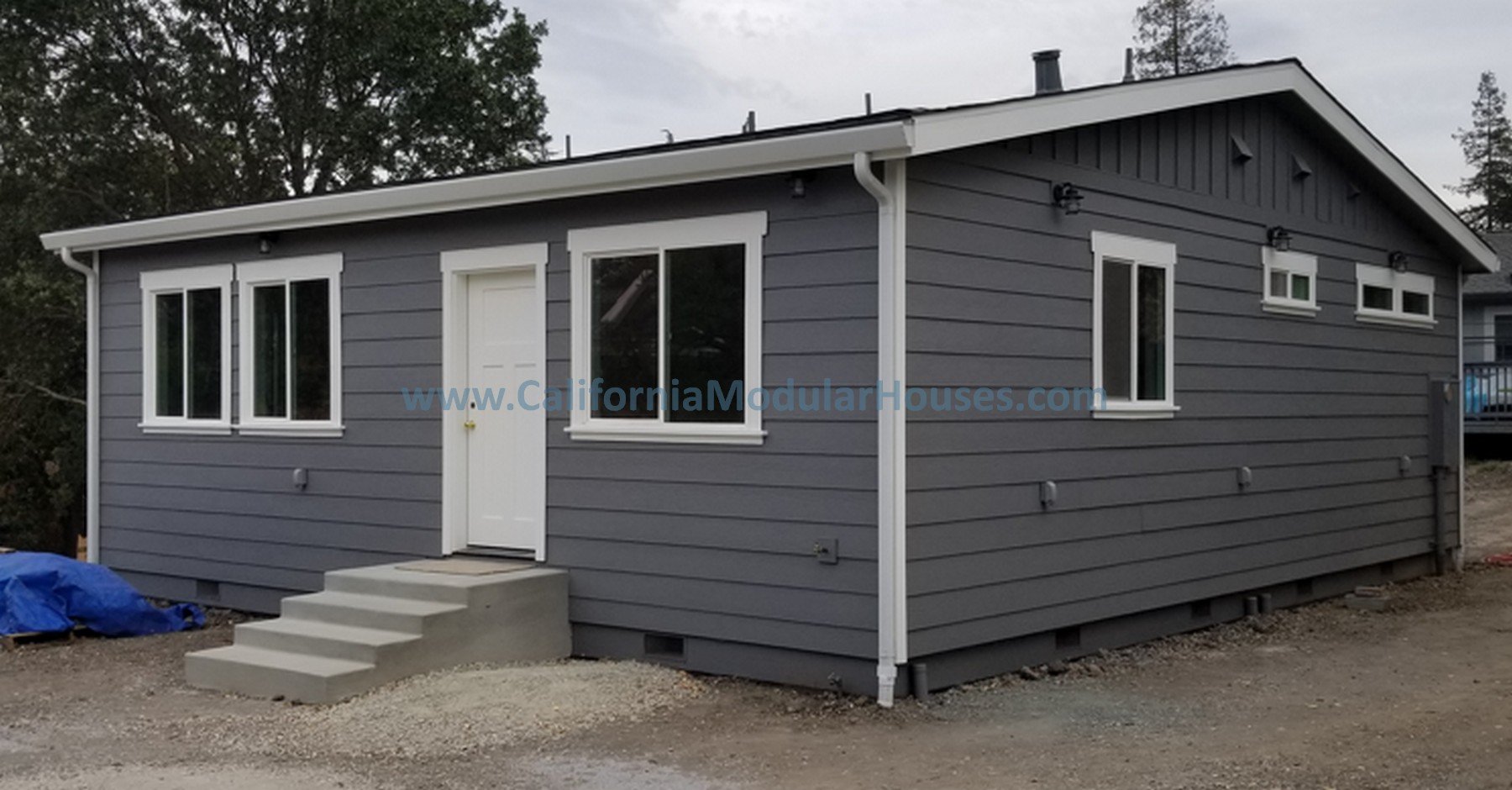 A small, modern, gray modular house with white trim and a white front door, featuring multiple windows and a set of steps leading up to the entrance. Walnut Creek, Contra Costa County California Modular ADU