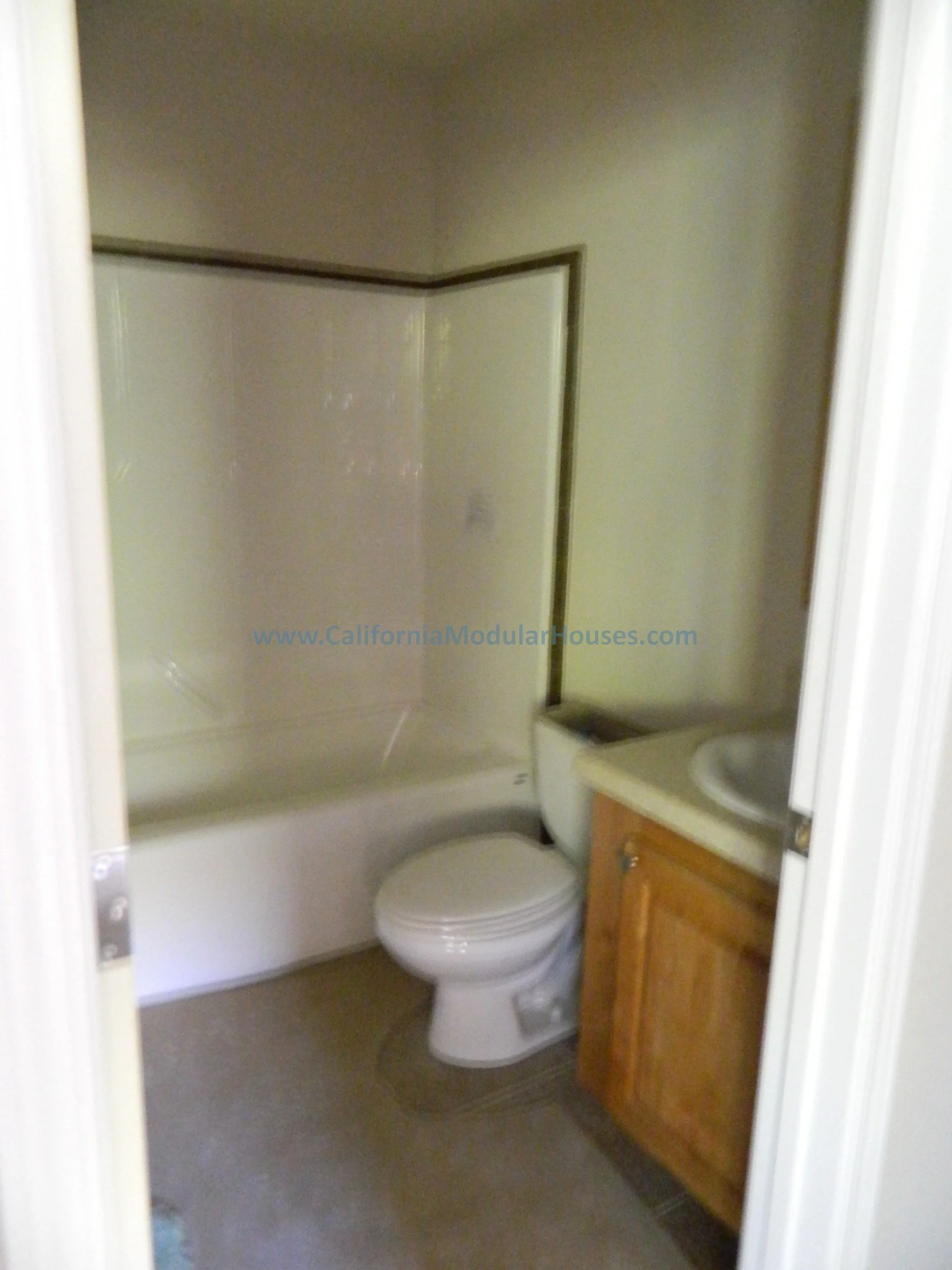 Small bathroom with a bathtub and shower combination, toilet, and wooden vanity with sink.