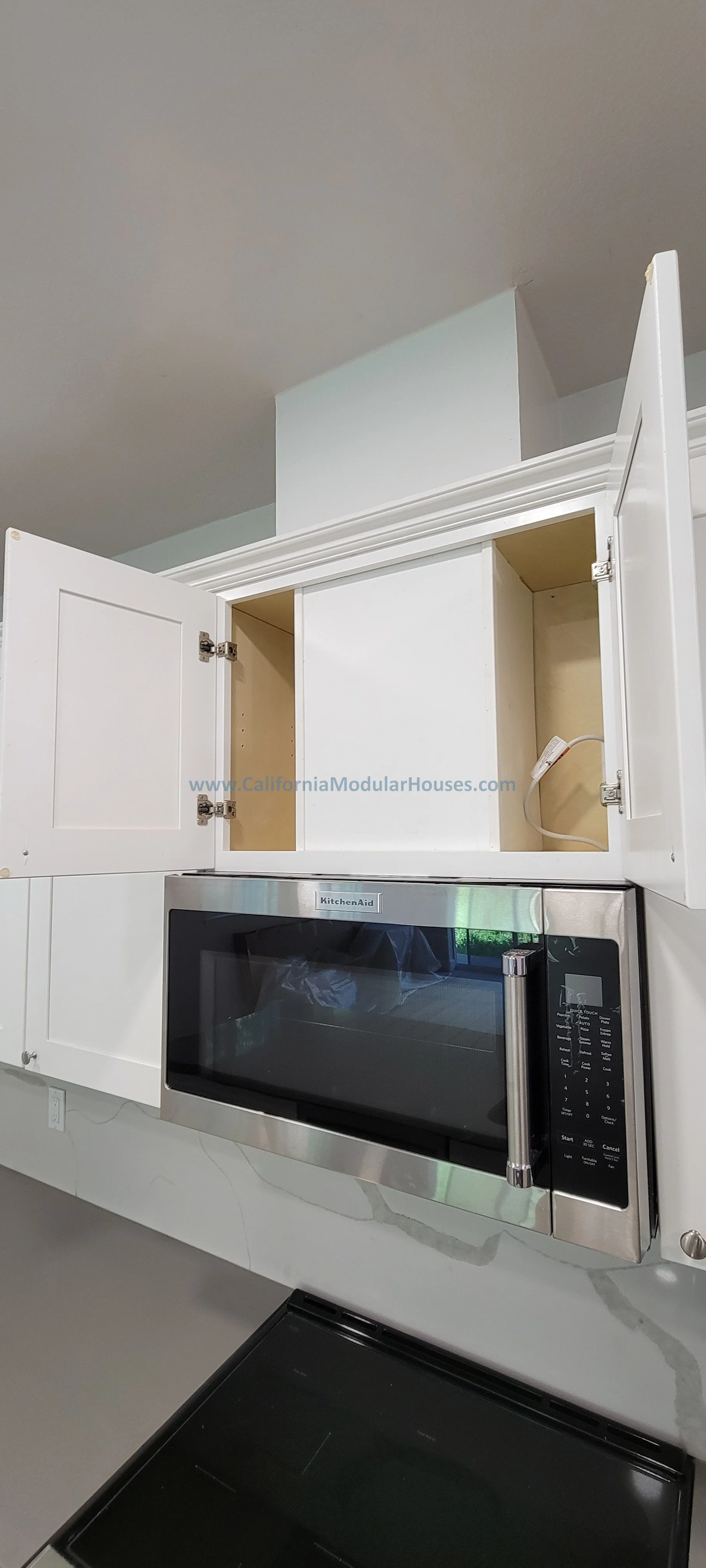 Open kitchen cabinet above a microwave with an incomplete upper section.