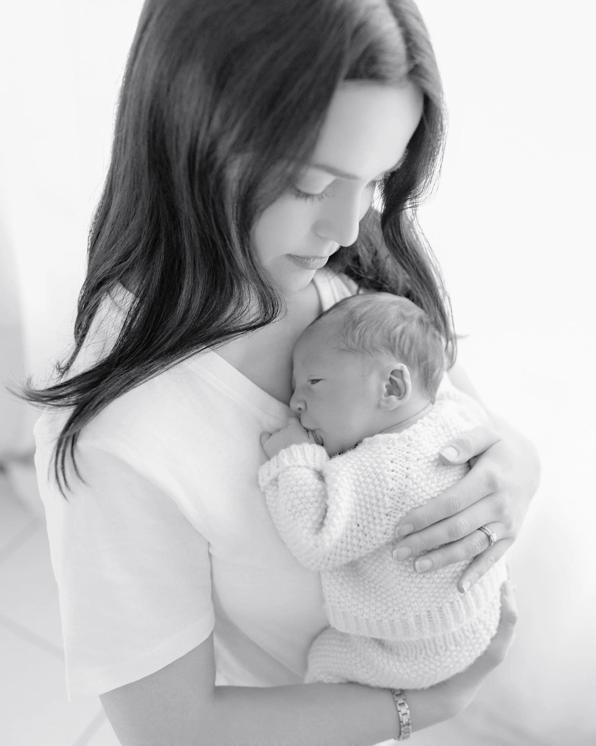 Mother cuddling her newborn baby during a soft natural lifestyle newborn session in Auckland