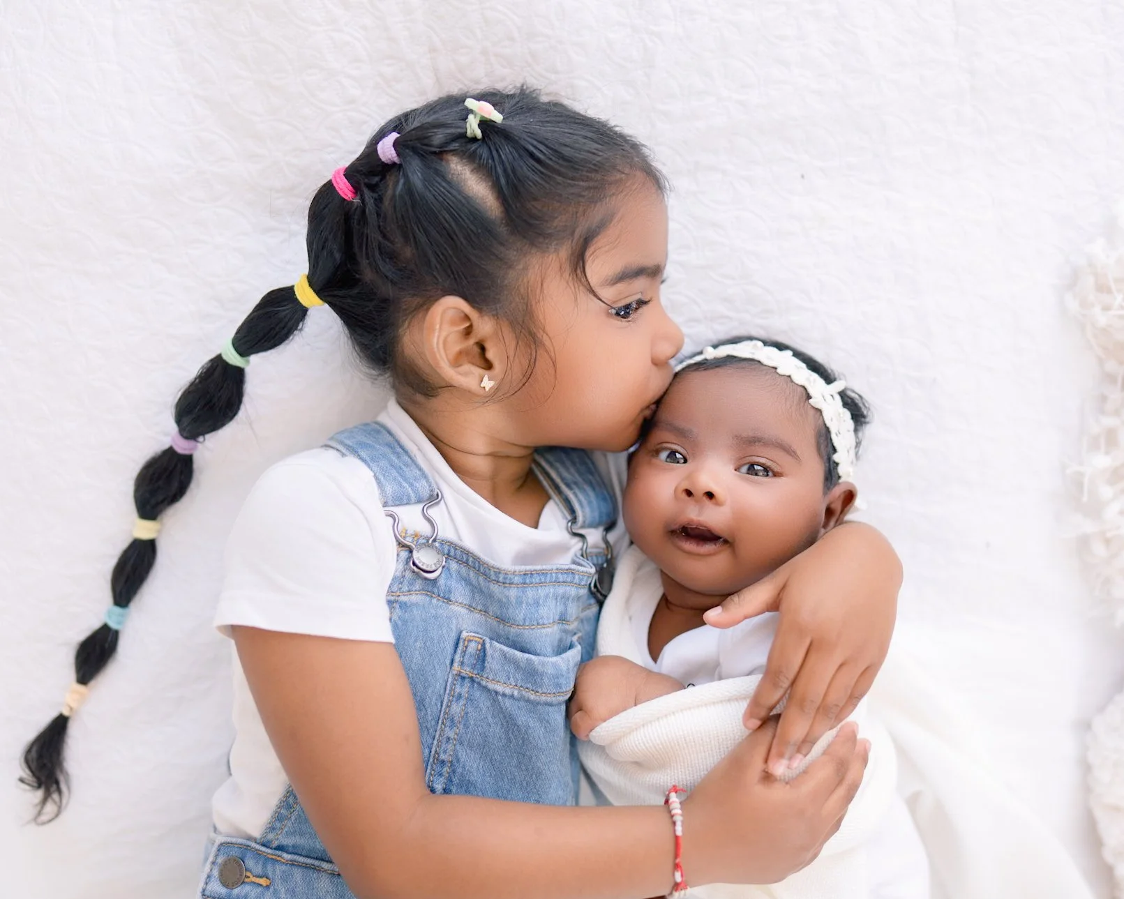 Big sister holding her newborn sibling during a split newborn photography session in Auckland