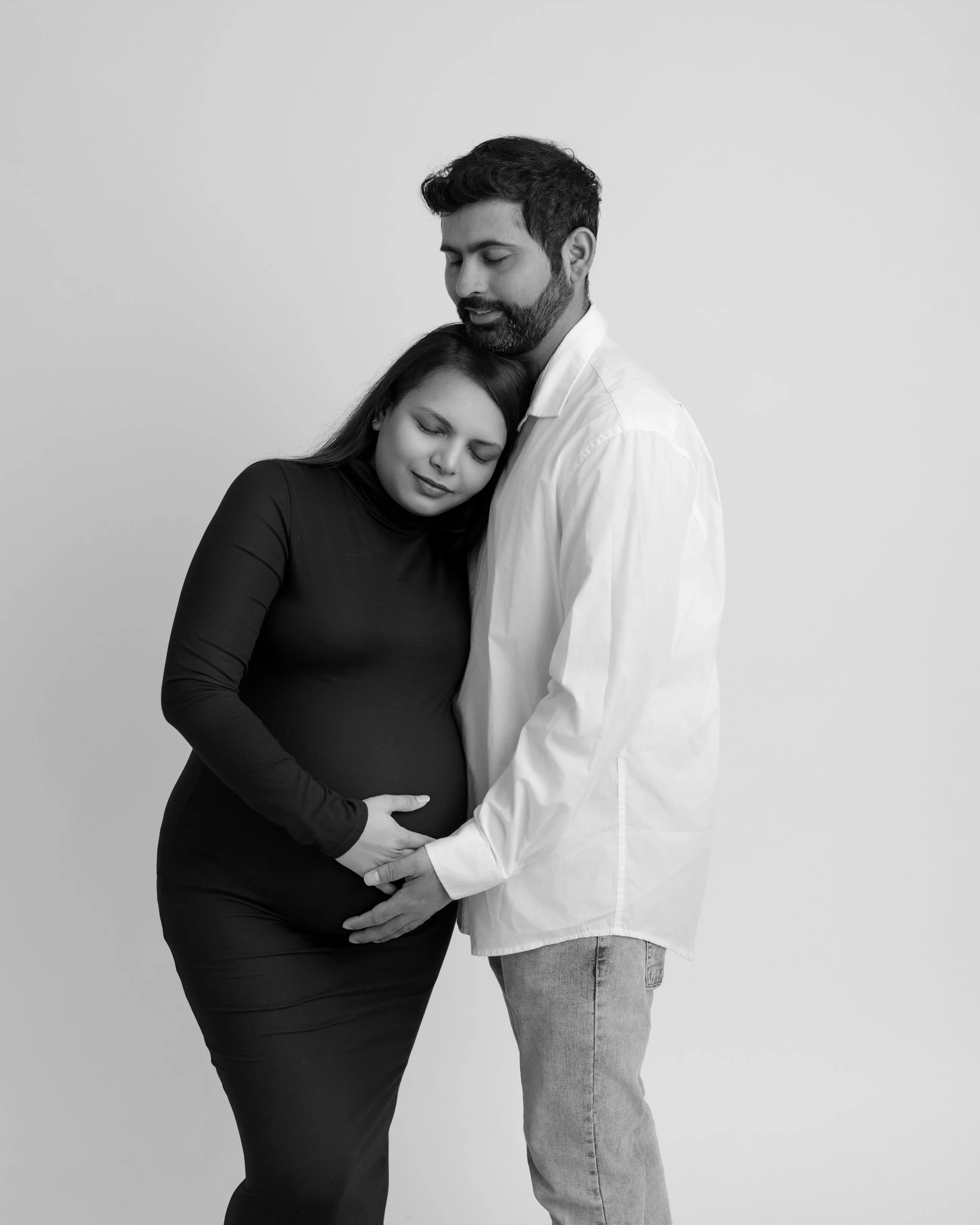 Expecting couple embracing during a black and white maternity photography session in Auckland.