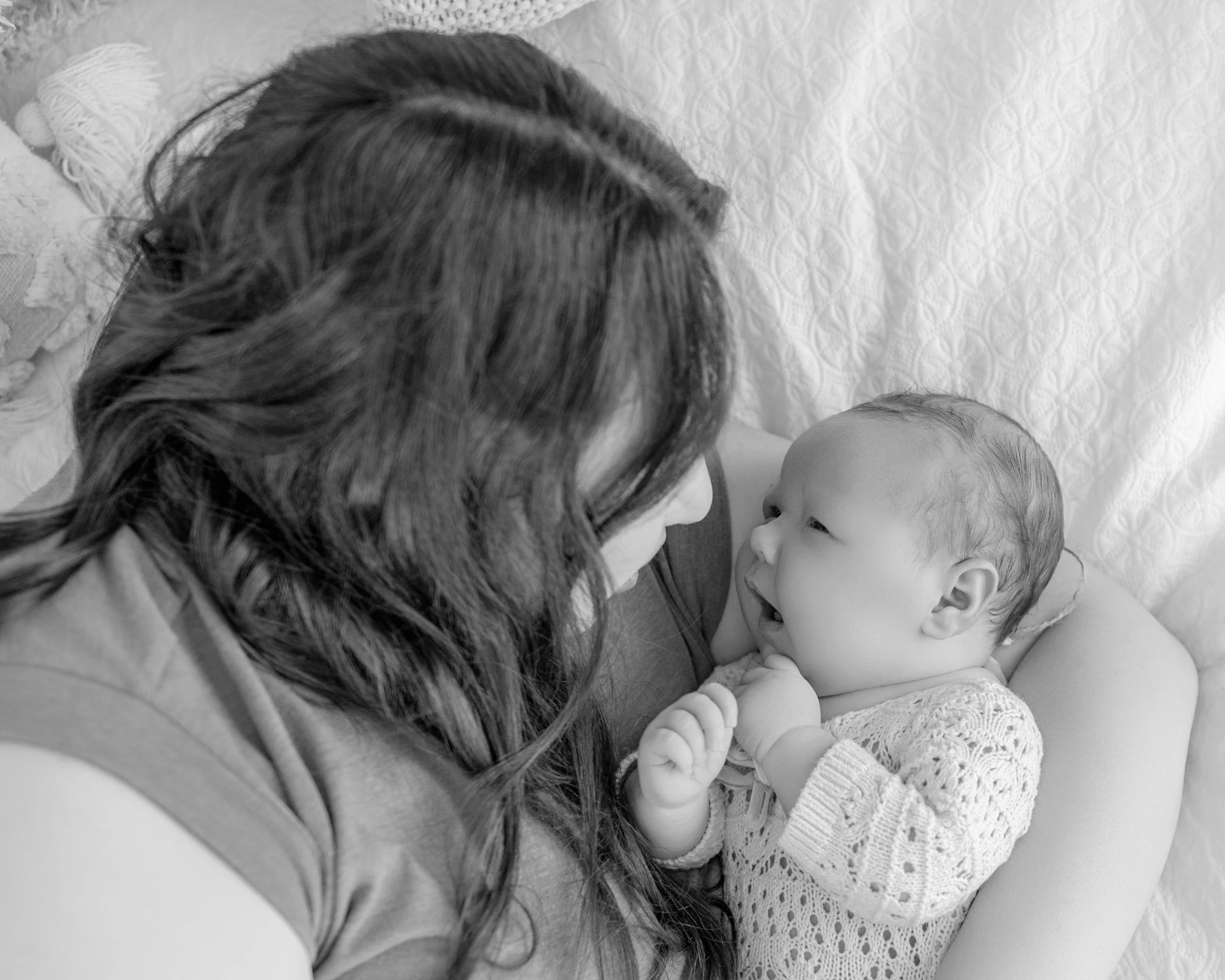 Mother looking lovingly at her newborn baby during a relaxed lifestyle newborn photography session in Auckland