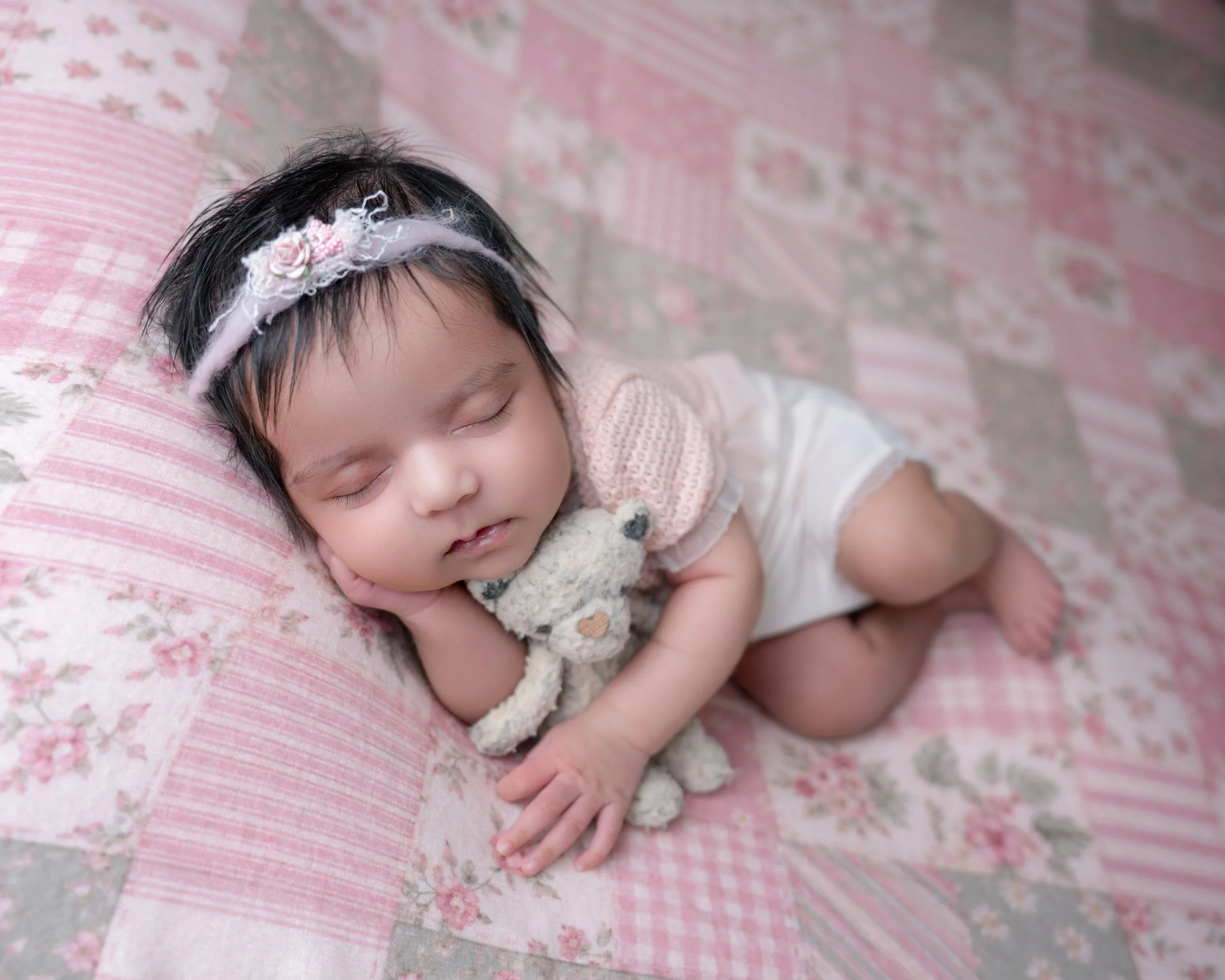 Newborn baby girl cuddling a teddy bear during an Auckland newborn photography session.