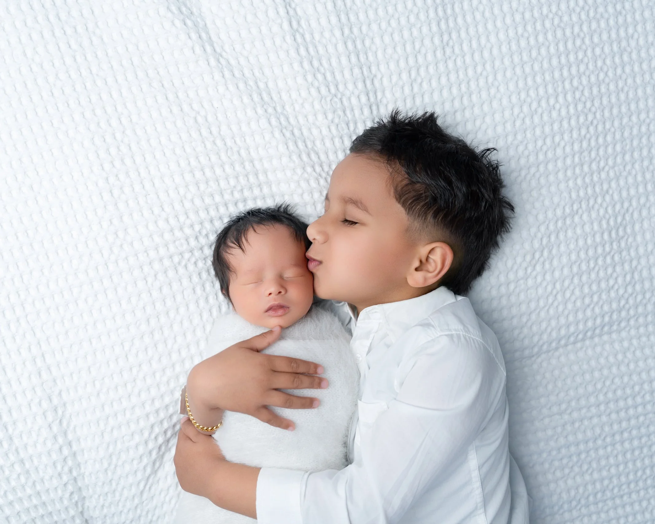 Older brother cuddling his newborn sibling