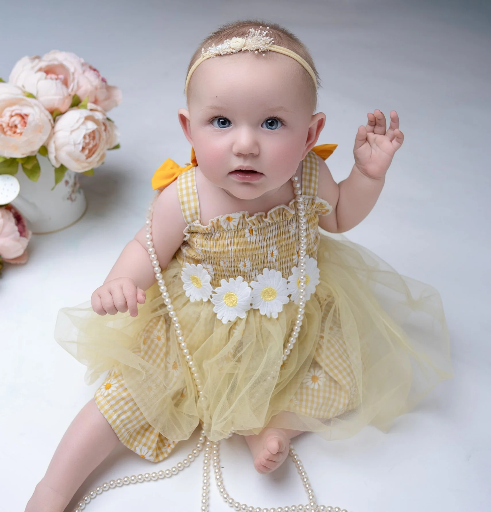 Baby girl in a yellow floral outfit during a styled Auckland milestone photography session.