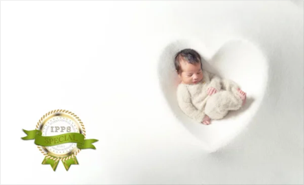 A sleeping baby in a heart-shaped cutout in white paper.