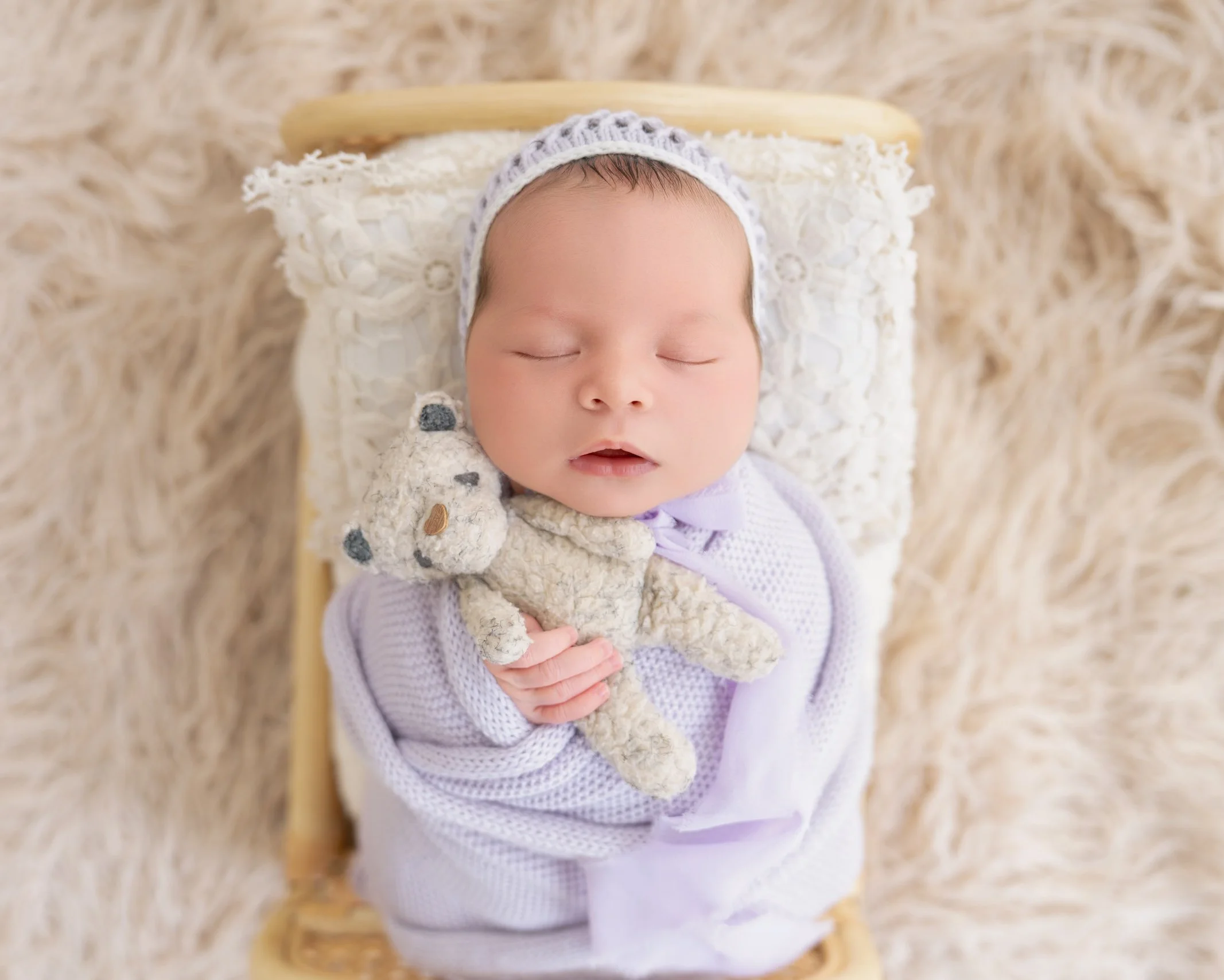 Sleeping newborn baby boy wrapped in a lavender swaddle during a mobile studio photography session on the North Shore.