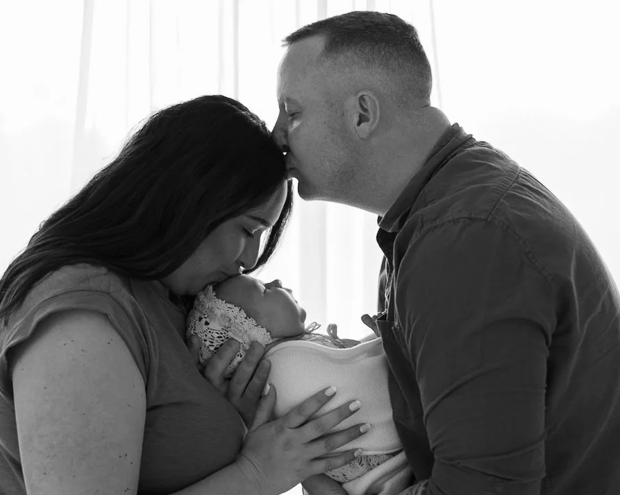 Mother and father sharing a quiet moment with their newborn baby during a natural family newborn photography session in Auckland