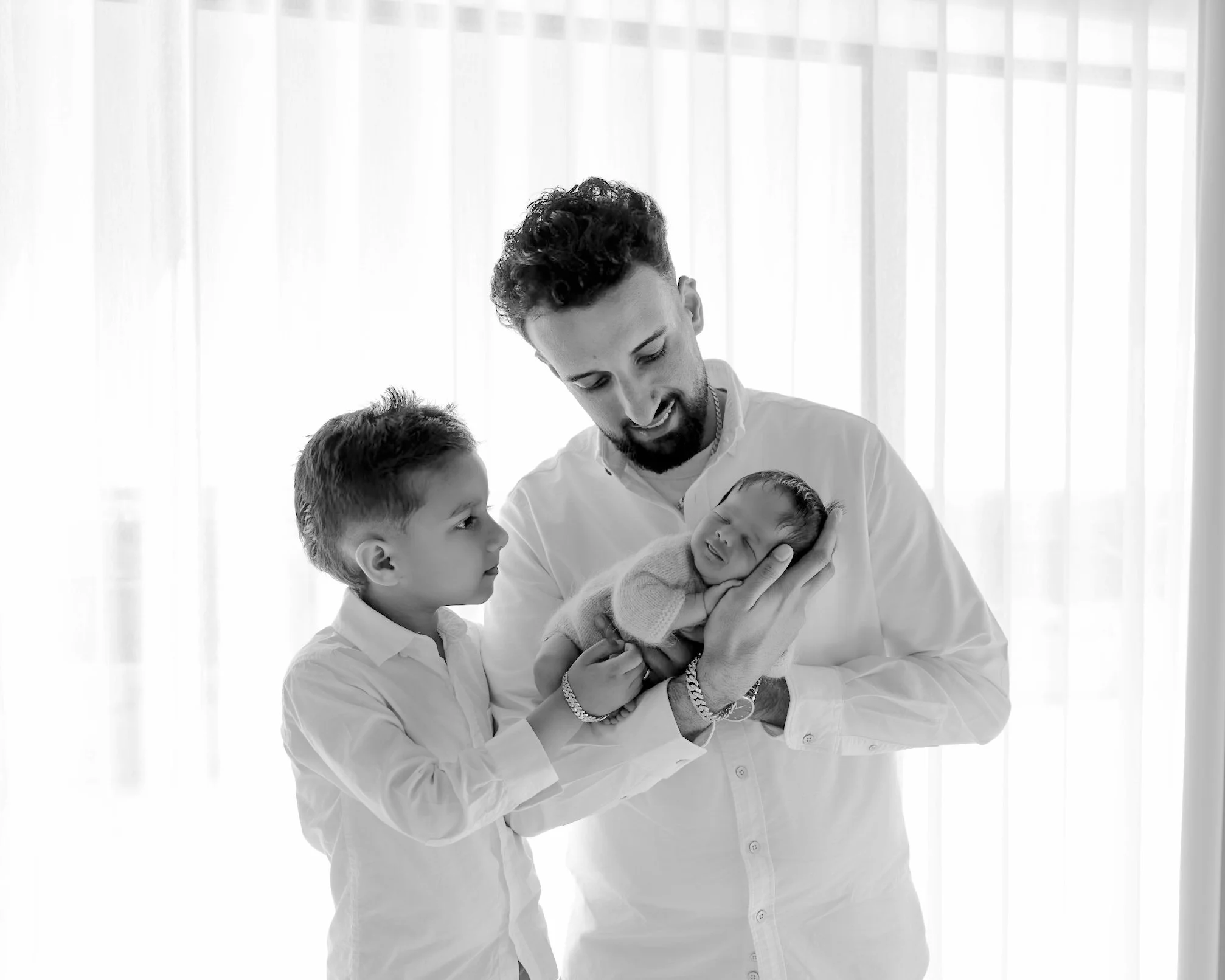 Father holding his newborn baby with his older son during an Auckland newborn photography session.