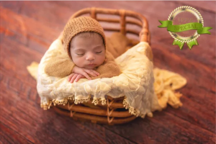 A sleeping baby in a wicker basket on a wooden floor.
