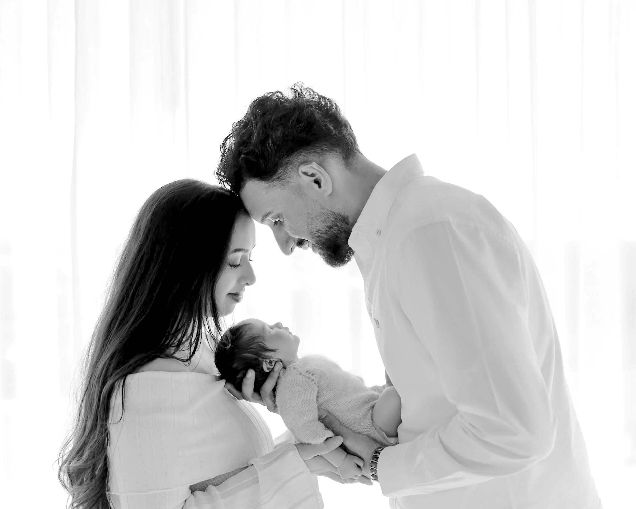 Parents holding their newborn baby together during a relaxed lifestyle newborn photography session in Auckland.