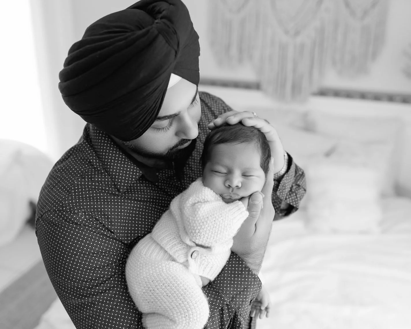 Dad gently holding his sleeping newborn baby during a natural and relaxed Auckland newborn photography session.