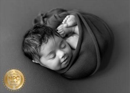 Newborn baby sleeping, wrapped in a blanket.