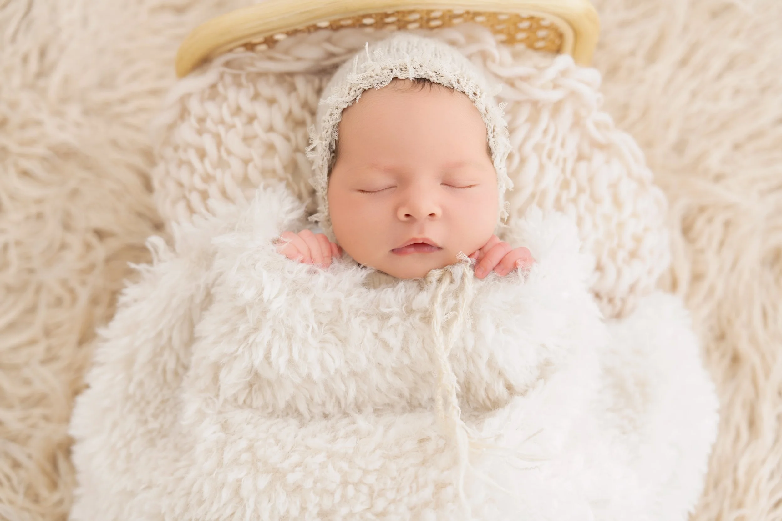 Posed newborn baby sleeping on a soft cream setup during an in-home newborn photography session in Auckland.