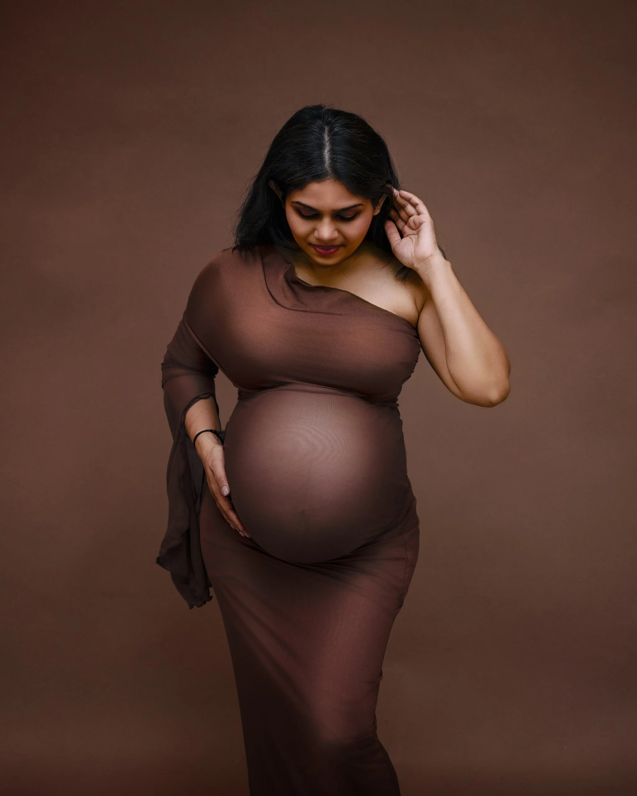 Studio maternity portrait in a fitted brown sheer gown during an Auckland maternity photoshoot.