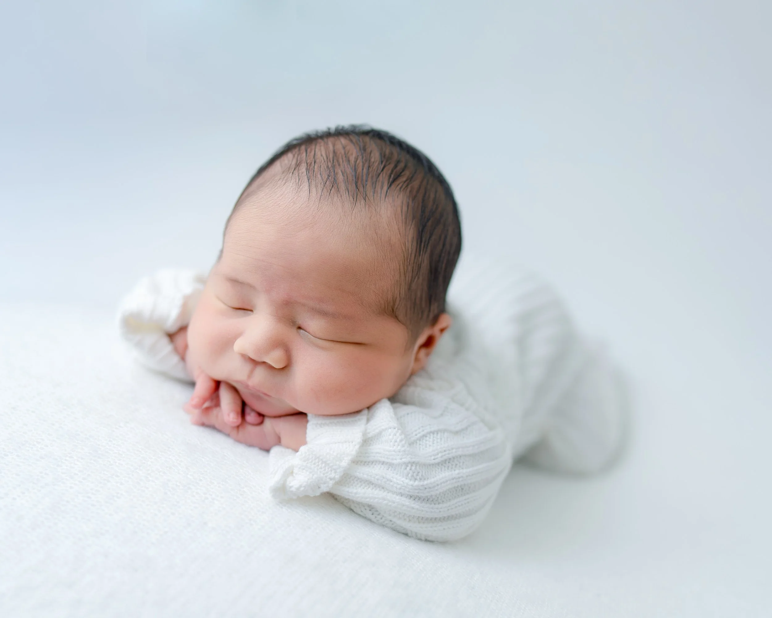 Close-up of a sleeping newborn baby safely posed during a West Auckland mobile studio photography session.
