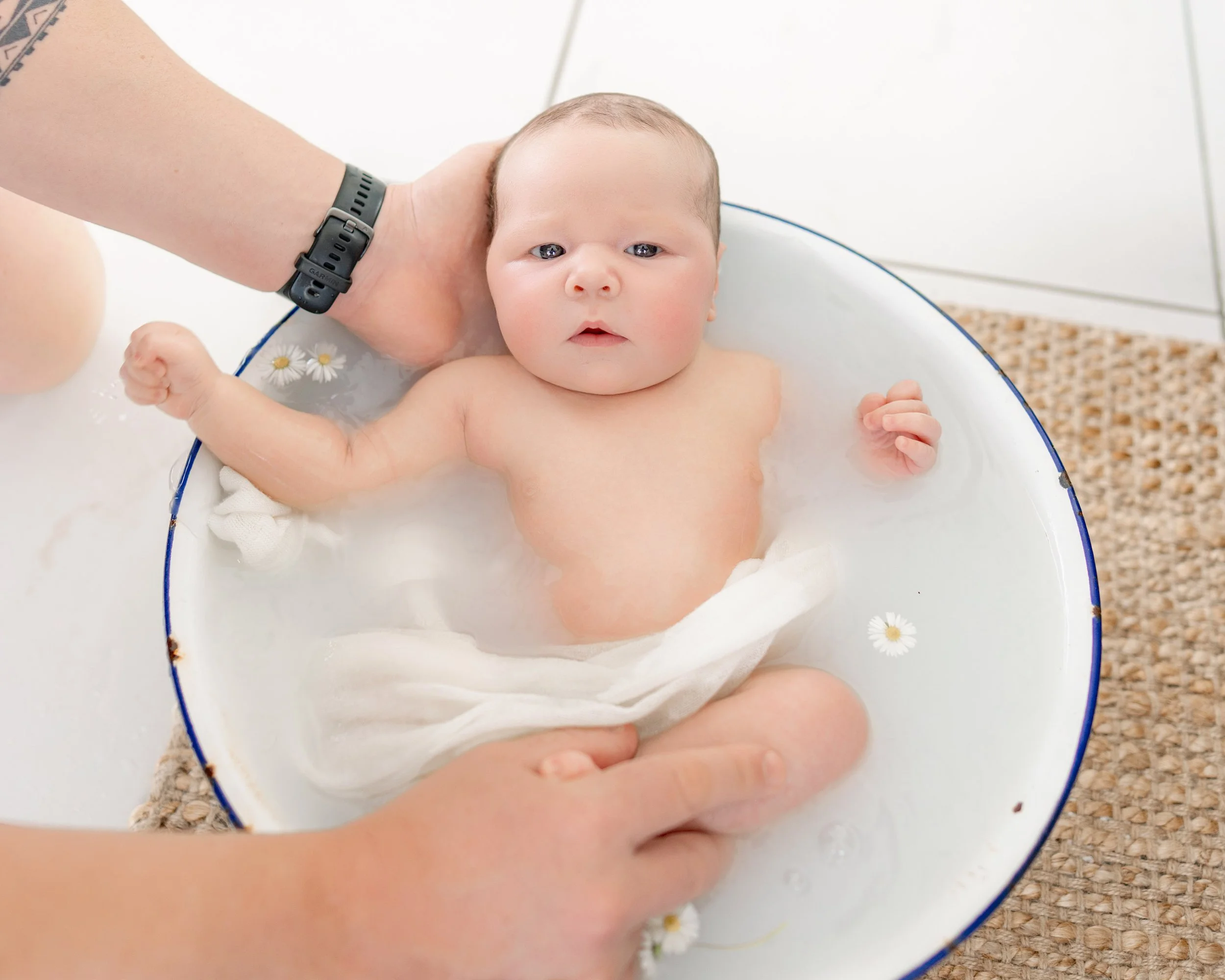 Newborn baby relaxing in a gentle milk bath during a styled newborn photography session in Auckland