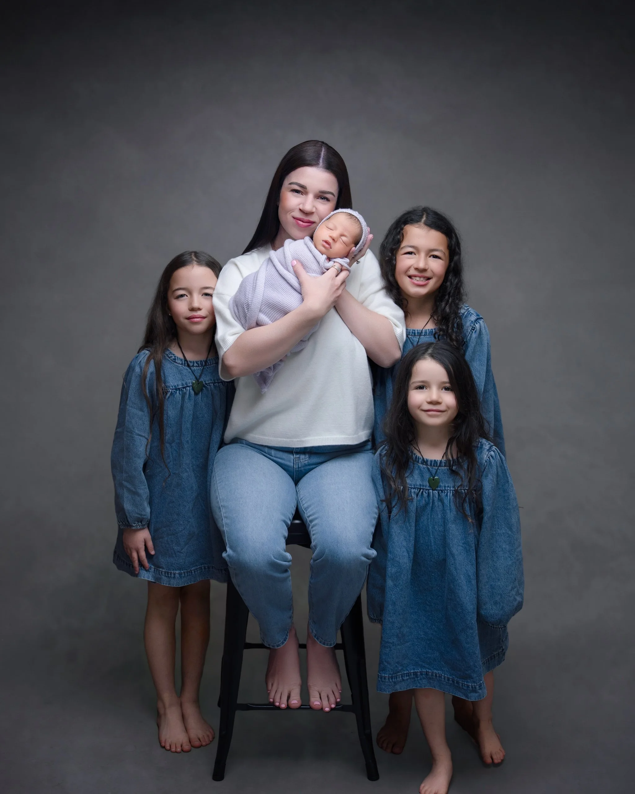 Mother holding her newborn baby with three older siblings during an Auckland newborn photography session.