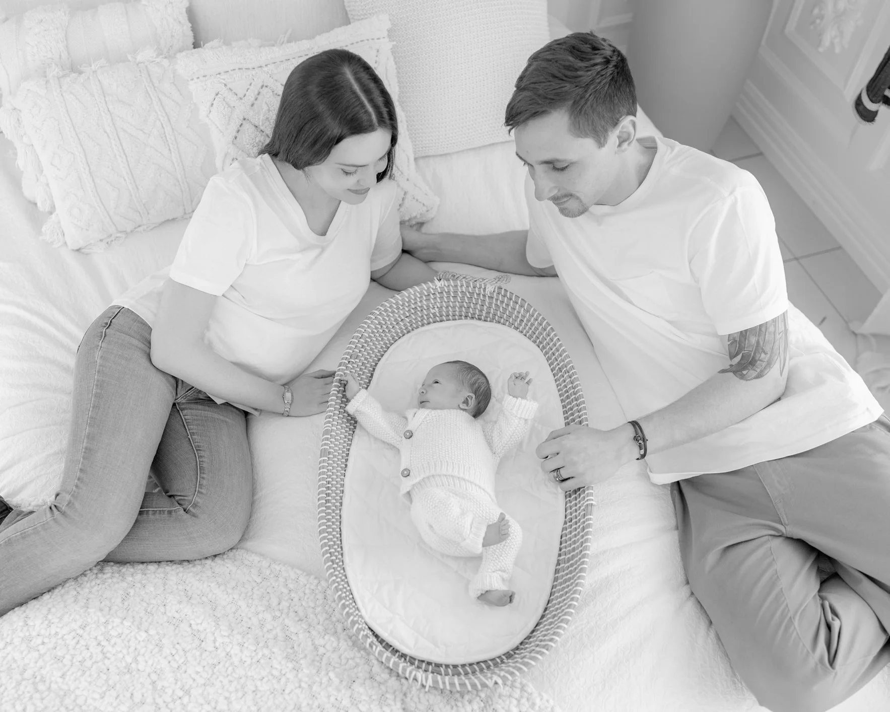 Mum and dad looking at their newborn baby in a bassinet during a relaxed lifestyle session