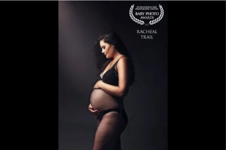 A pregnant woman with long dark hair wearing fishnet lingerie, holding her belly, against a dark background with a baby photo awards logo and text.
