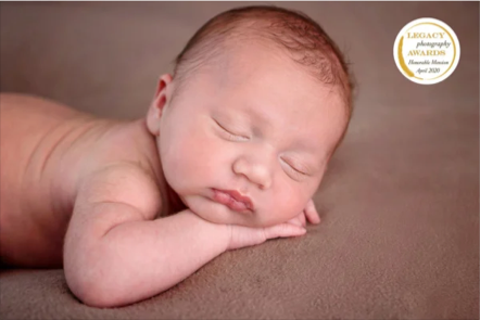 Close-up of a sleeping newborn baby lying on its stomach with its head resting on its arm.
