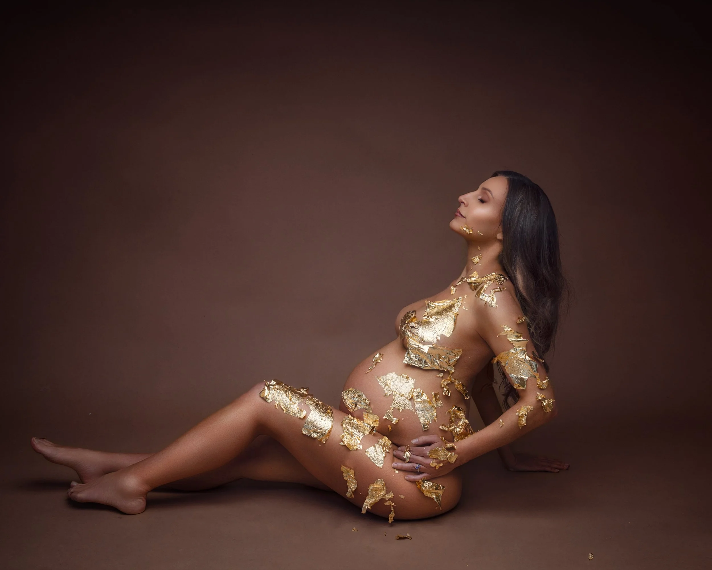 Pregnant woman posed with gold leaf body styling during an Auckland maternity photography session.