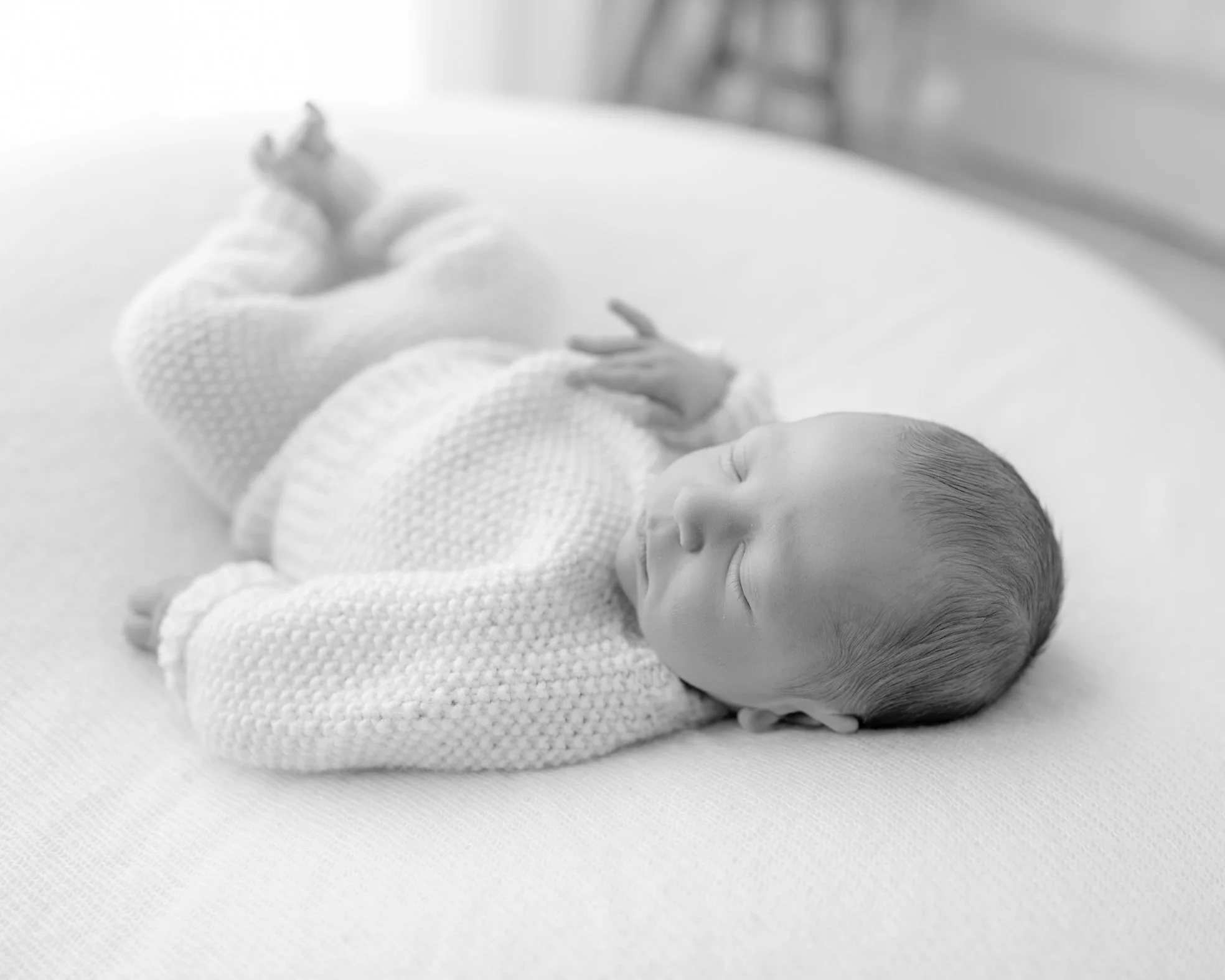 Sleeping newborn baby in a knitted outfit during a natural lifestyle newborn session in Auckland