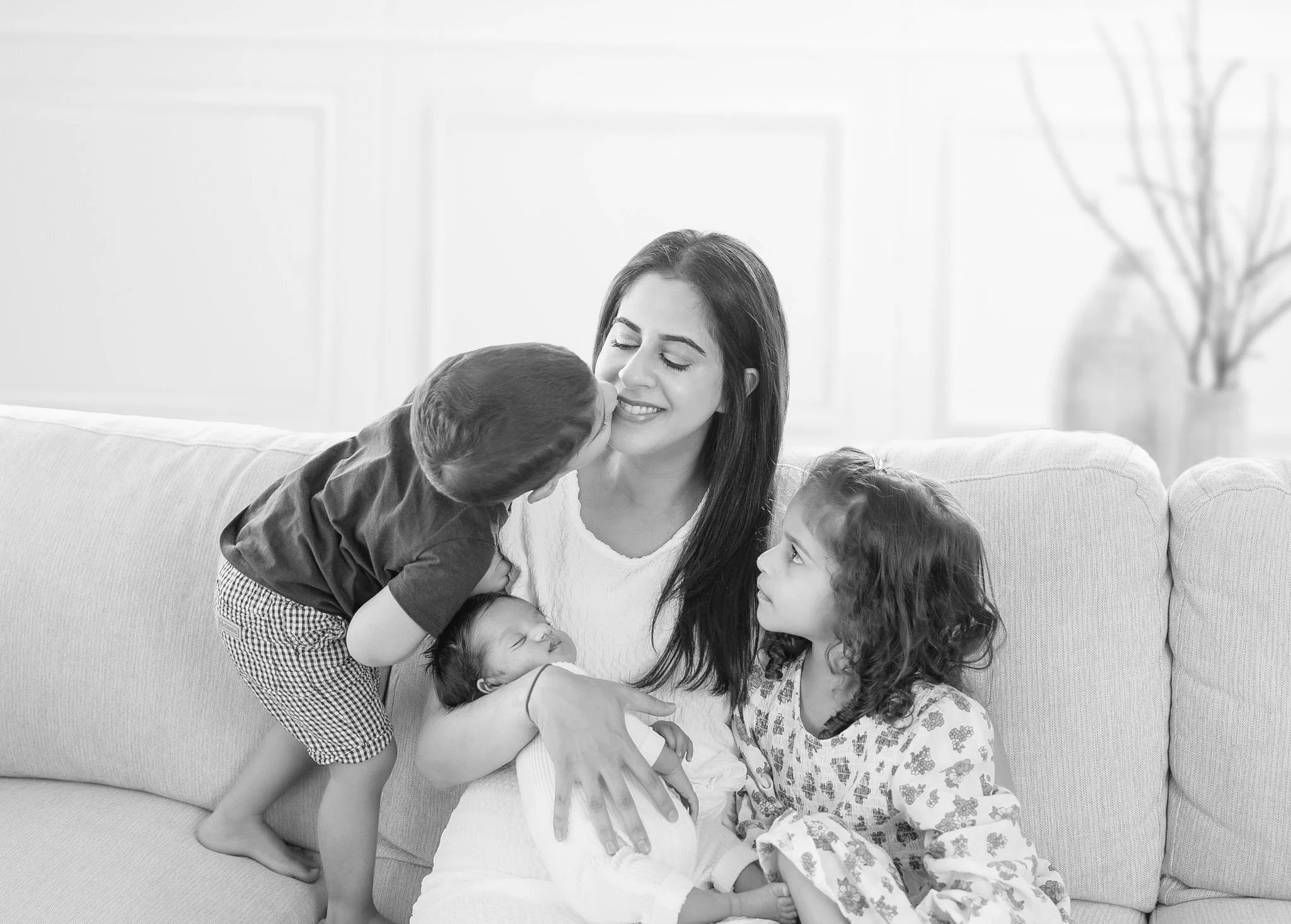 Mother sharing a playful moment with her two older children while holding their newborn baby during an in-home newborn photography session in Auckland.