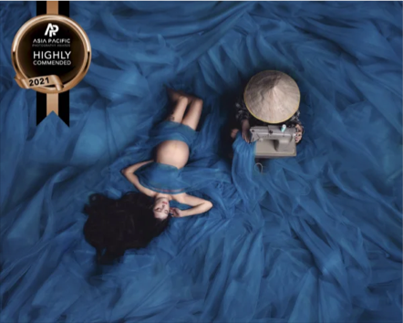 A woman lying on blue fabric with a vintage typewriter on her side. An award badge in the top left corner reads 'Asia Pacific Highly Commended 2021.'