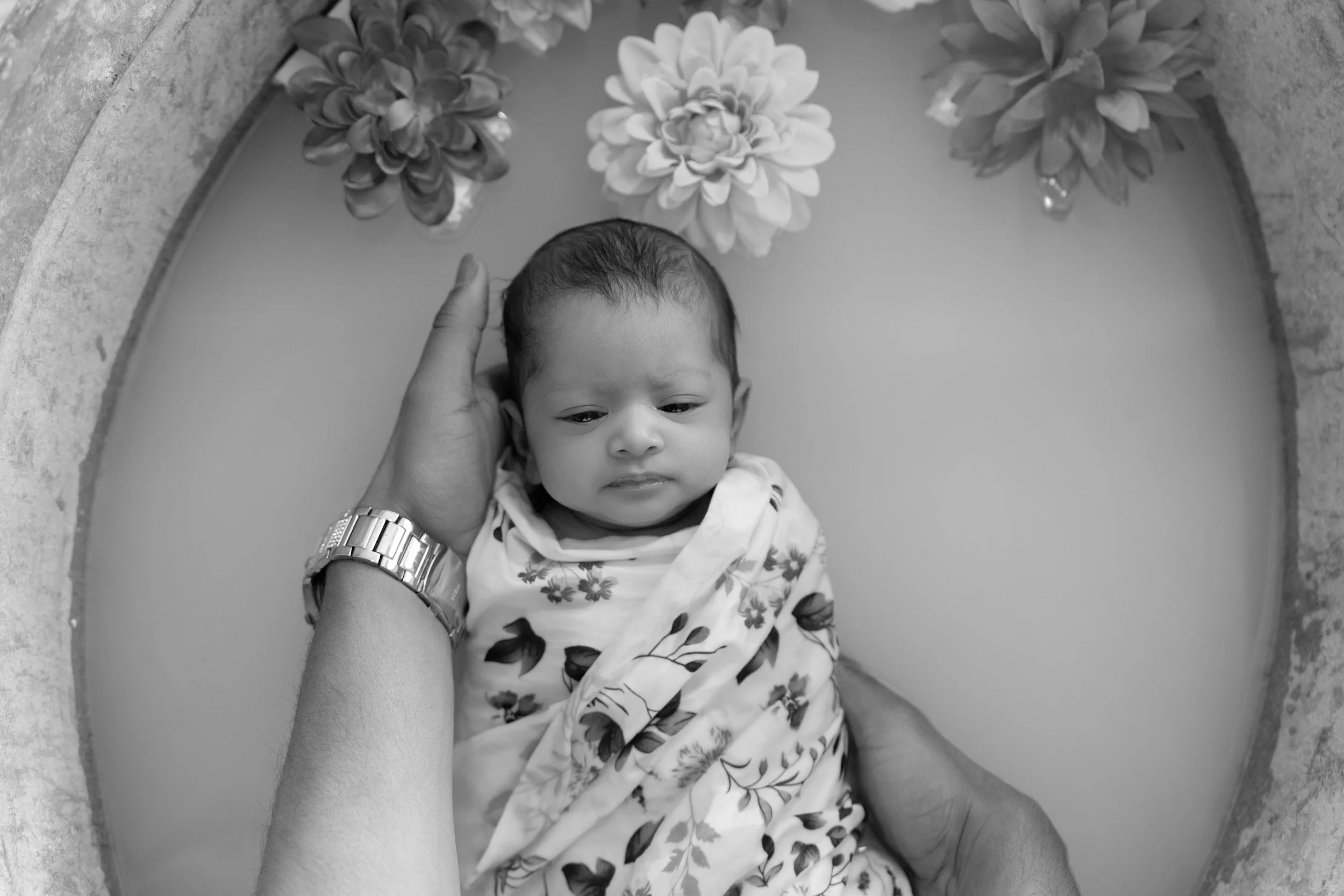 Awake newborn baby wrapped in a floral wrap during an in-home newborn photography session in Auckland.